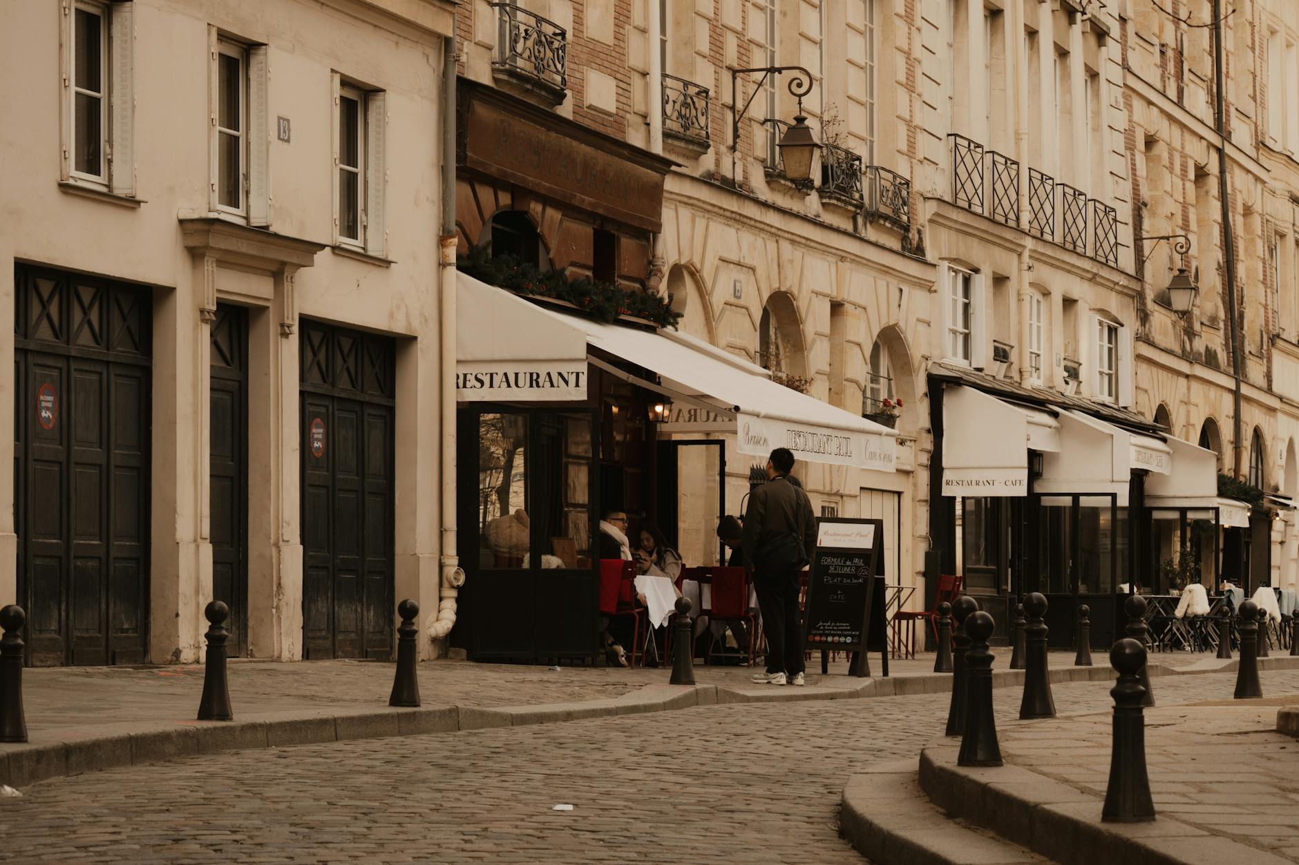 Cobblestone street in Paris with cafes and classic architecture, evoking a vintage urban mood.