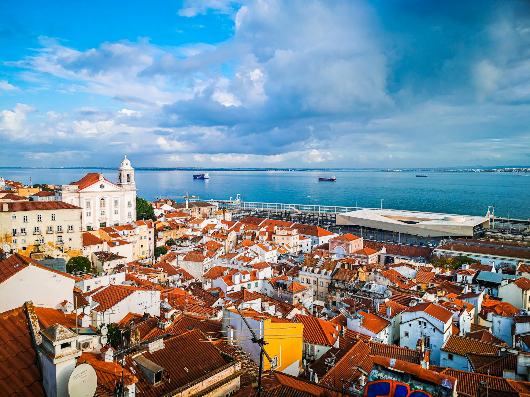 Captivating aerial view of Lisbon's historic rooftops by the scenic coastal shore.