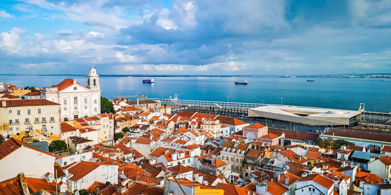Captivating aerial view of Lisbon's historic rooftops by the scenic coastal shore.