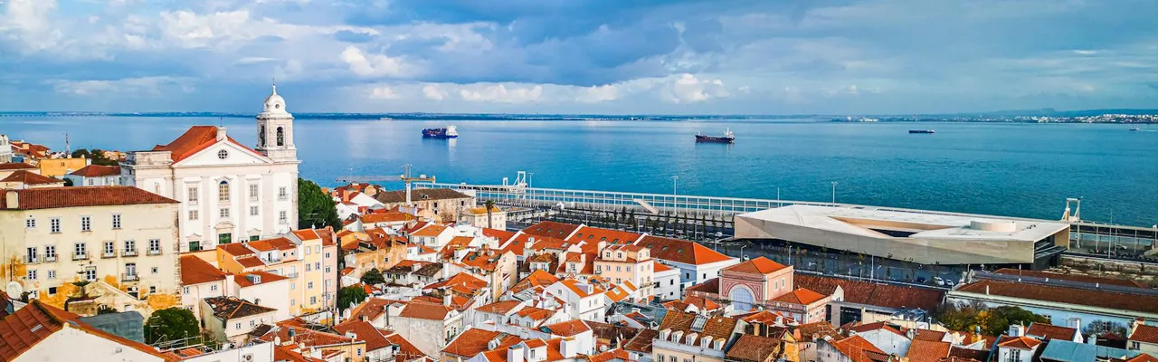 Captivating aerial view of Lisbon's historic rooftops by the scenic coastal shore.