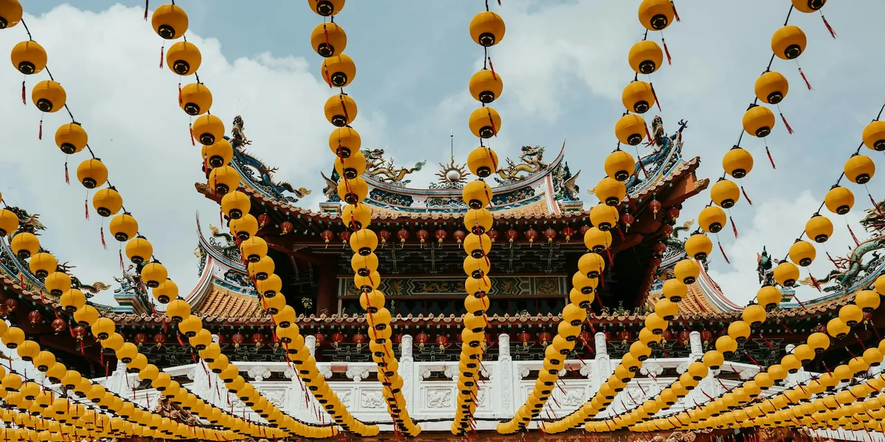 Colorful Chinese temple adorned with vibrant yellow lanterns under a clear sky.