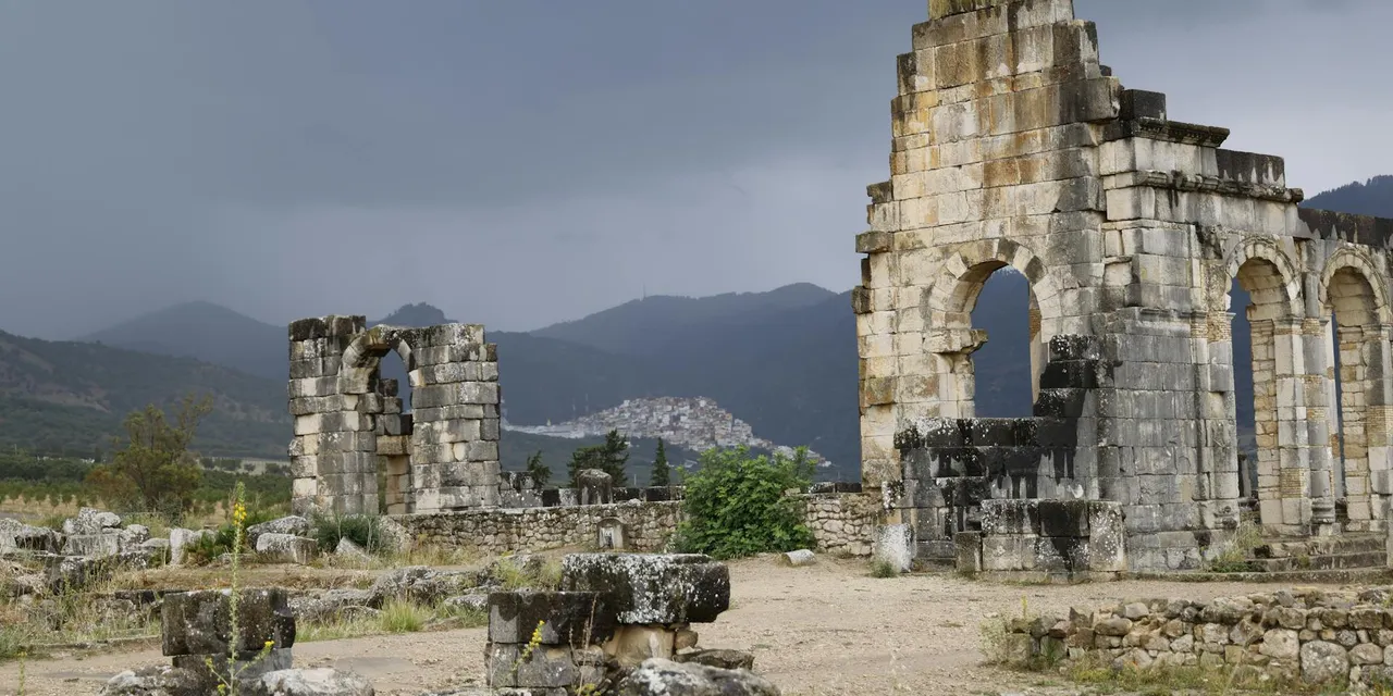 Explore the ancient Roman ruins of Volubilis, Morocco, amidst a dramatic landscape.