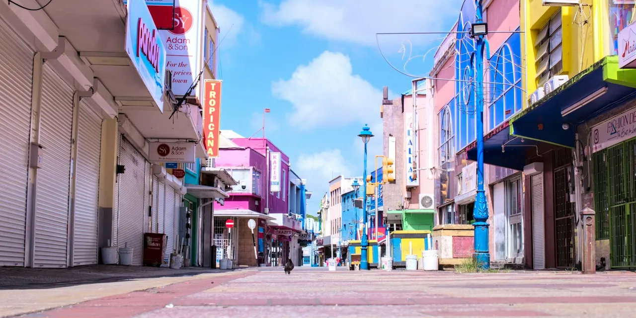 Vibrant downtown street in Bridgetown, Barbados with colorful buildings and a clear blue sky.
