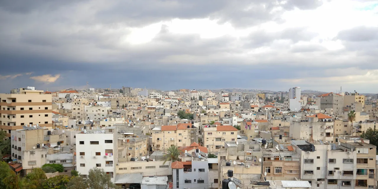 Rooftop panorama of a Palestinian city under dramatic storm clouds, Palestine