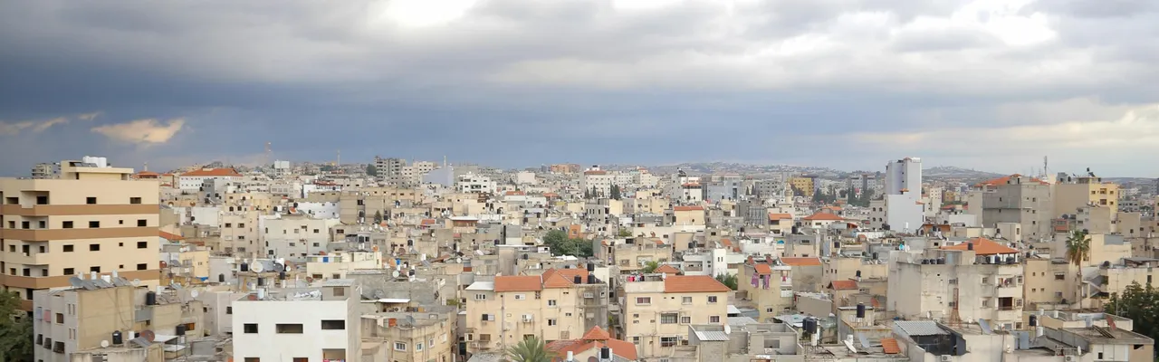 Rooftop panorama of a Palestinian city under dramatic storm clouds, Palestine
