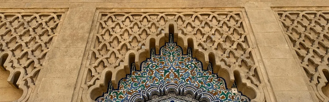 Intricate Moroccan tilework and stone carving in a traditional architectural design.