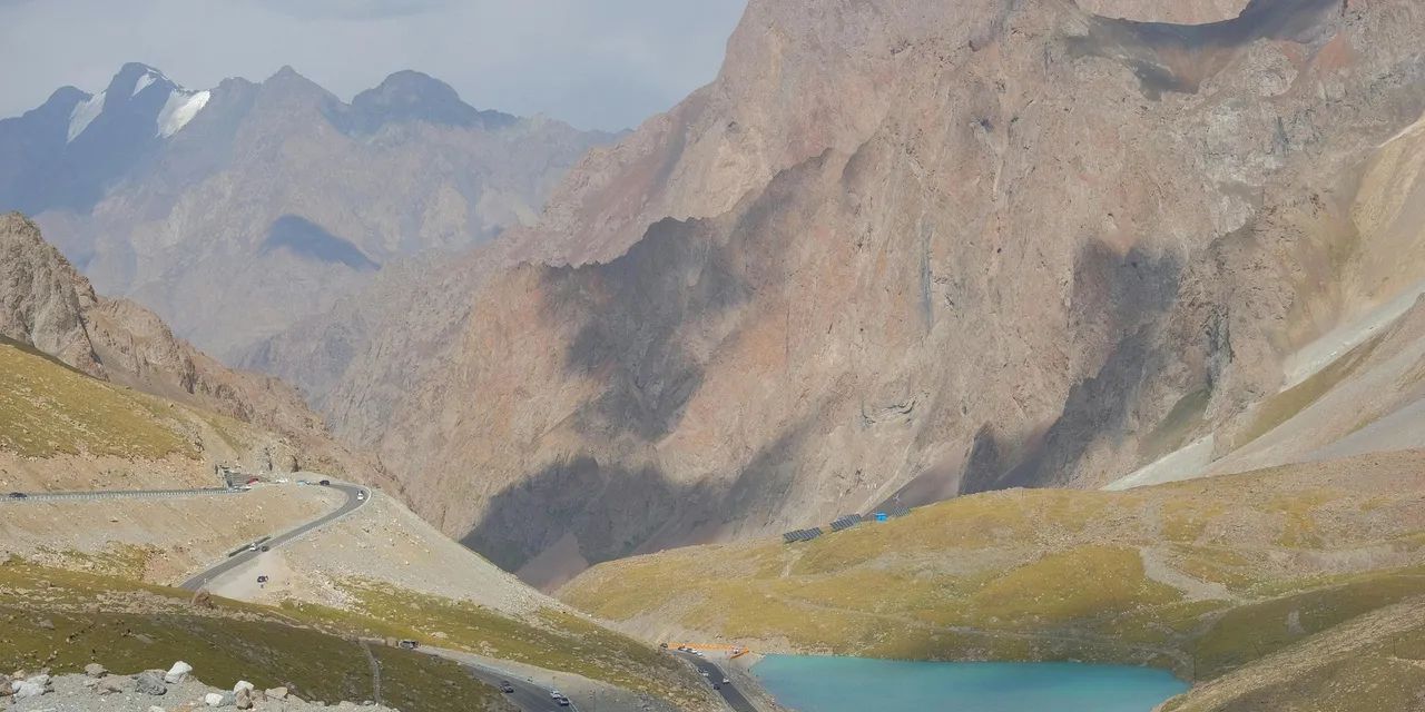 Turquoise alpine lake beside a winding mountain road in the Pamir Highway, Tajikistan