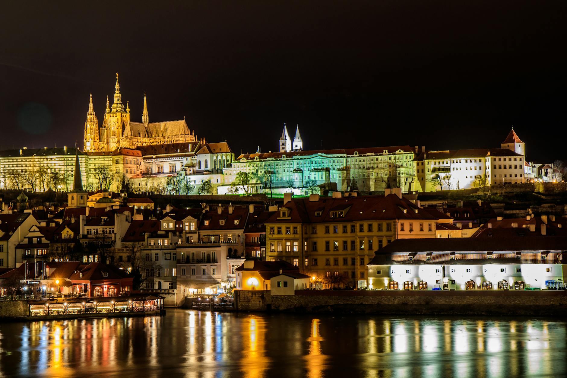 Captivating night view of the illuminated Prague Castle reflecting in the Vltava River.