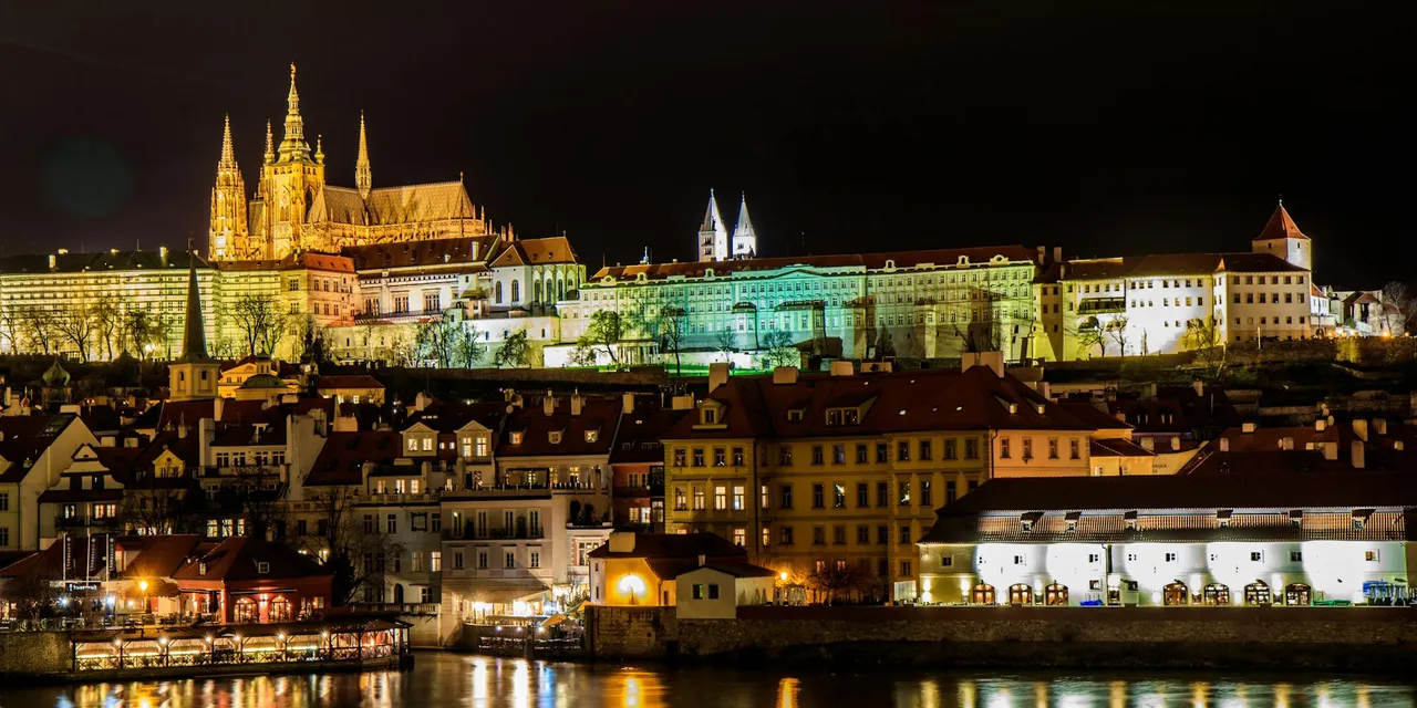 Captivating night view of the illuminated Prague Castle reflecting in the Vltava River.