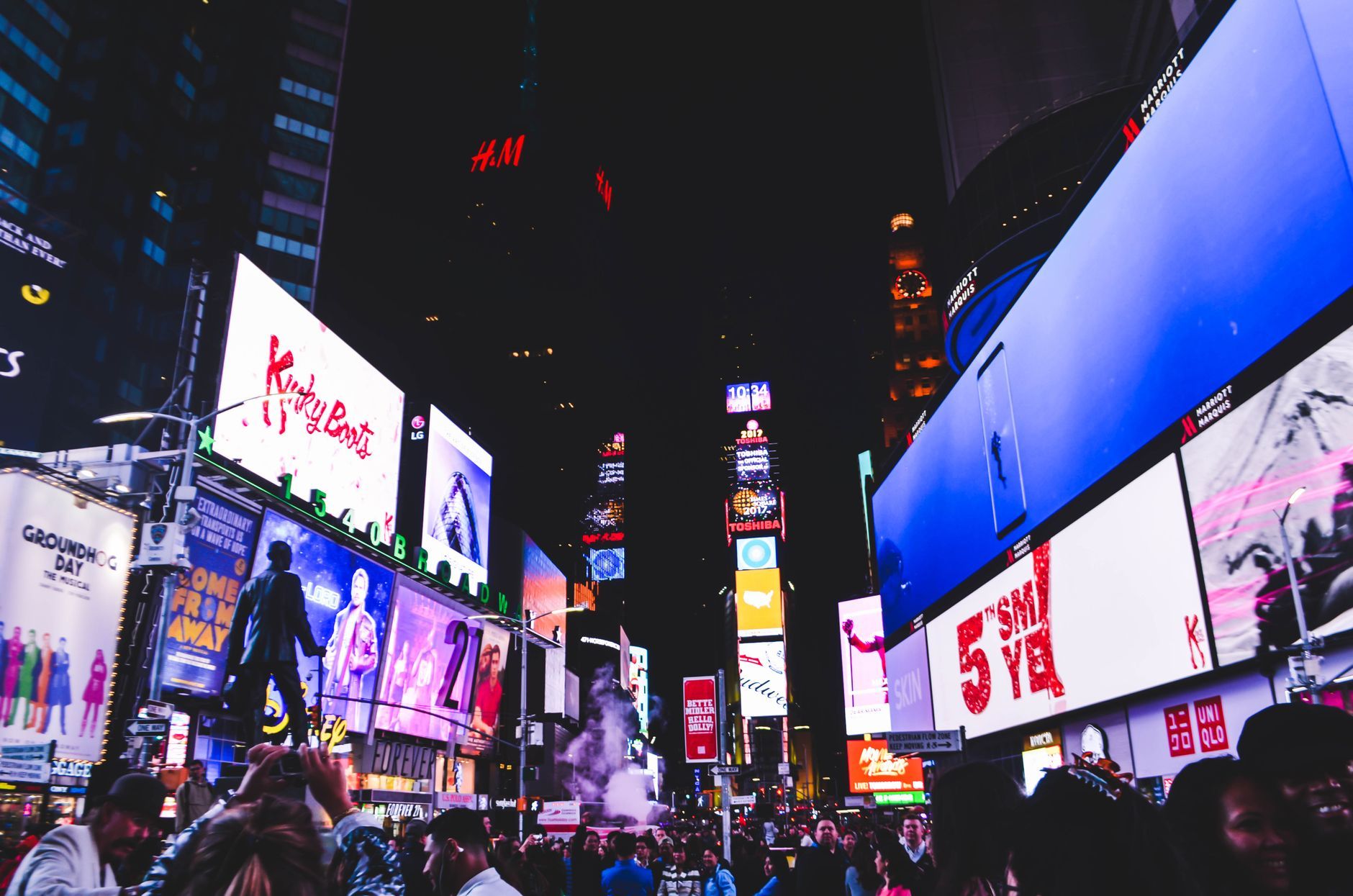Bustling Times Square in New York City illuminated by bright digital billboards and a lively crowd at night.