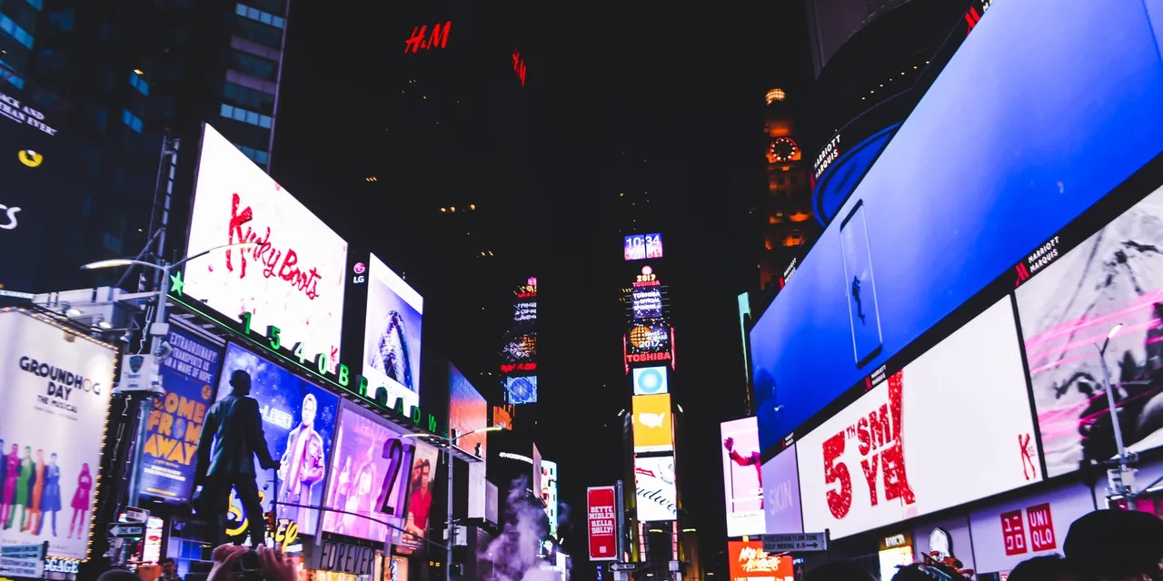 Bustling Times Square in New York City illuminated by bright digital billboards and a lively crowd at night.