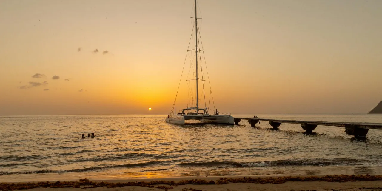 Magical sunset scene with a yacht near the pier on a serene evening in Dominica.