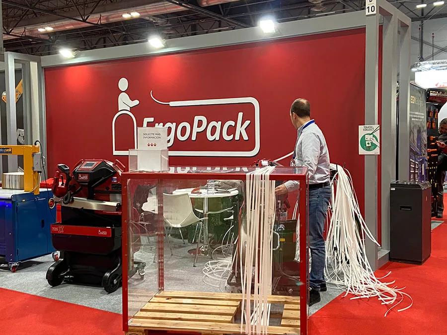 Técnico manejando una máquina flejadora en el stand de un fabricante durante una feria industrial