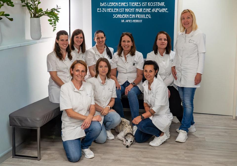 Eight women in white uniforms and a dog pose in a veterinary clinic. TVZ Scheibbs