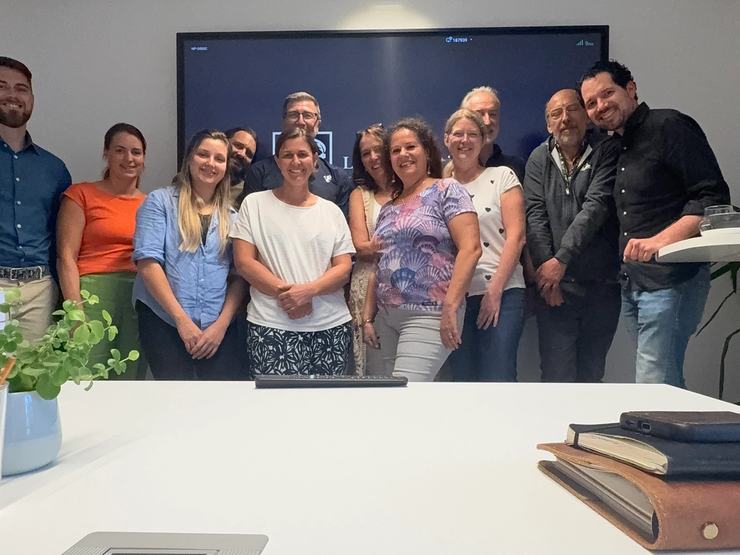 A diverse group of smiling colleagues standing in a modern meeting room.
