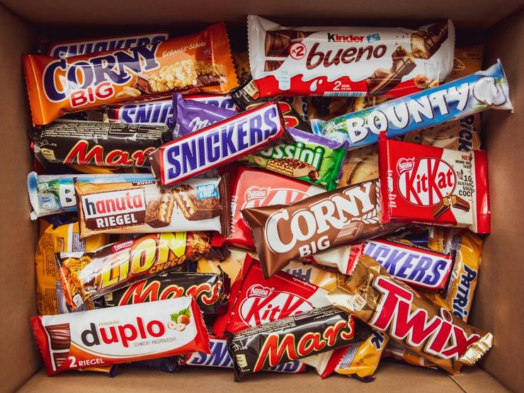 A cardboard box filled with assorted candy bars.