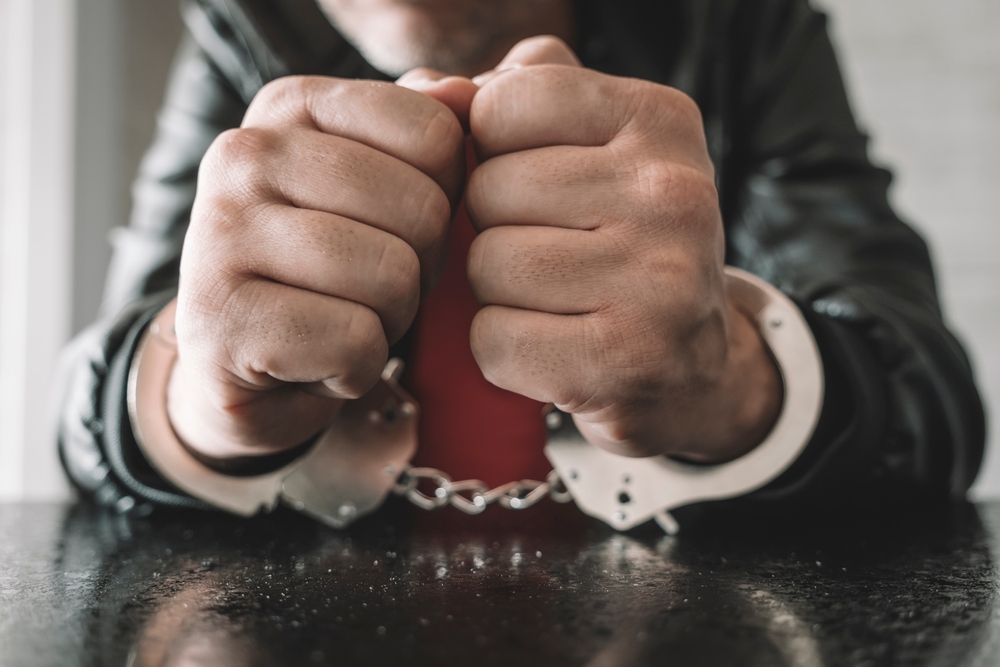 Image Person in handcuffs resting their hands on a table, symbolizing the serious consequences of criminal charges in New Jersey