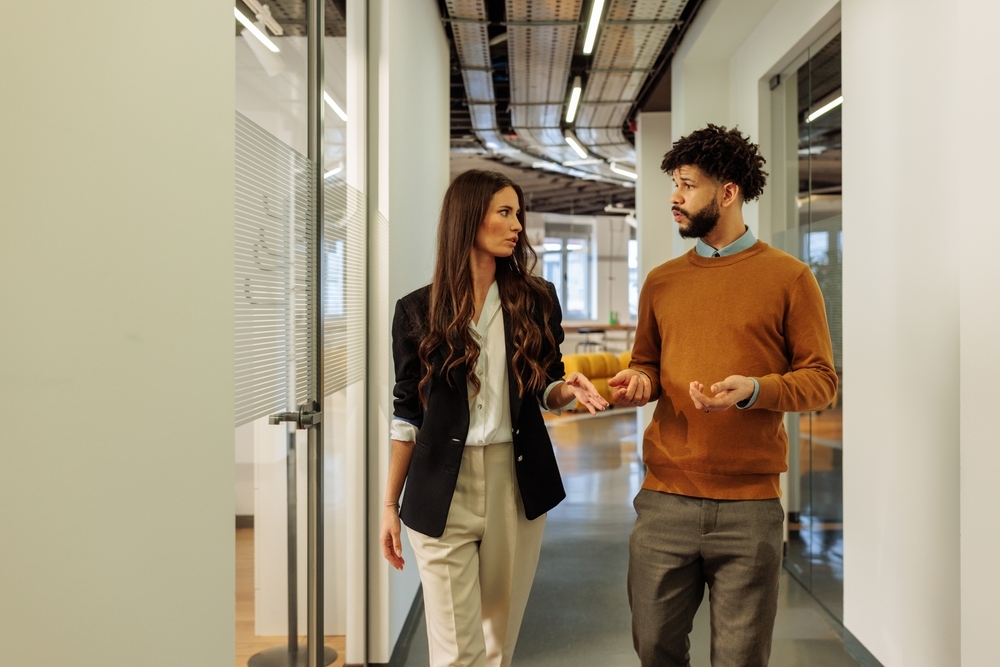Image Two employees discussing pay concerns in office hallway related to wage discrimination and unequal pay in the workplace