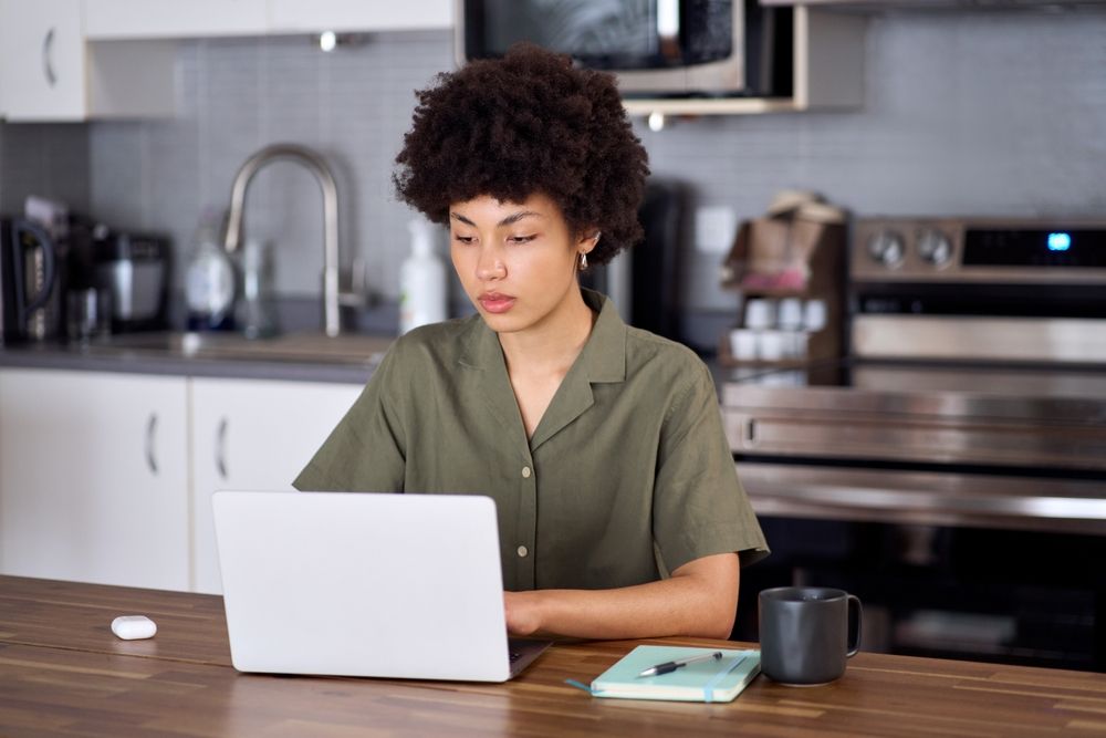 Dimly lit home office with laptop screen glowing from unread Slack and Zoom notifications, symbolizing tension in remote work