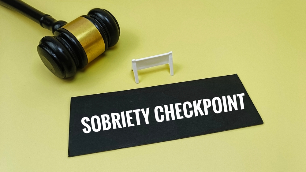 Image Sobriety checkpoint sign on a table next to a judge’s gavel, illustrating New Jersey holiday DUI checkpoint enforcement in December.