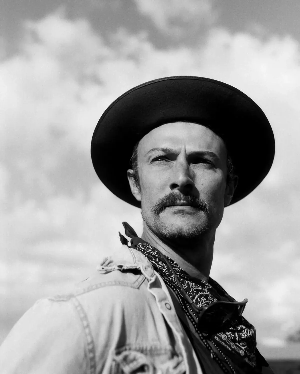 Richie Conry, founder of Moon Wolf Provisions in Richardson TX — black-and-white portrait, cowboy hat and bandana against open Texas sky