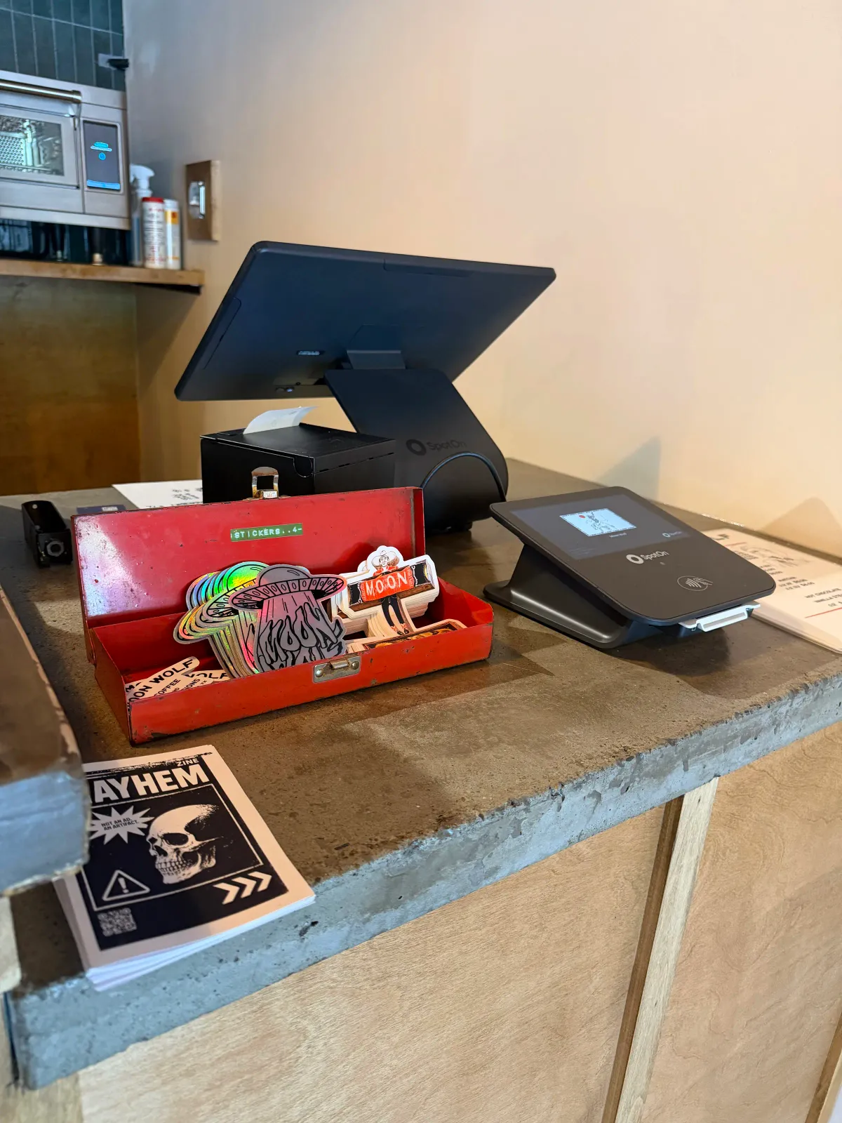 Point-of-sale counter with a Moon Wolf sticker tray and Mayhem zine at the coffee bar in Moon Wolf Provisions, Richardson Texas