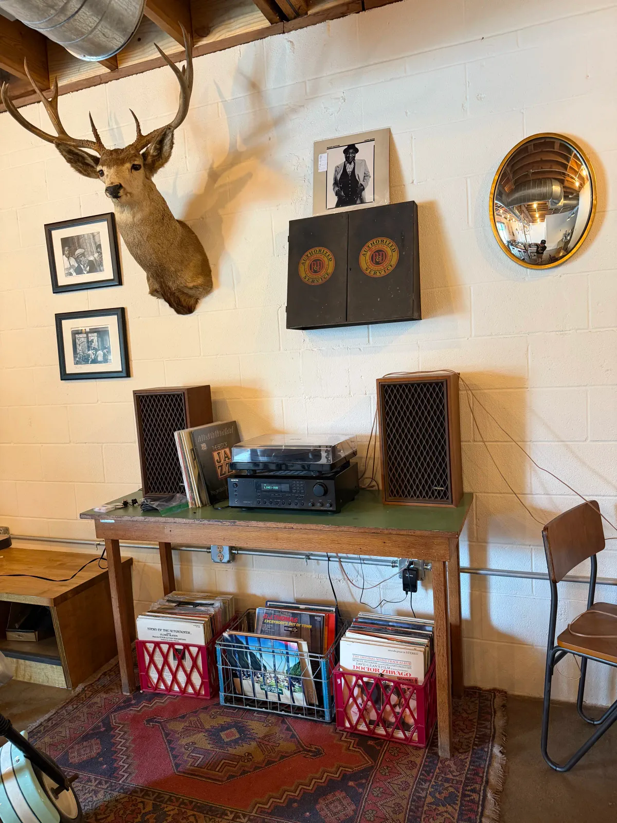 Turntable, vinyl crates, and a mounted taxidermy buck in the lounge corner at Moon Wolf Provisions coffee shop in Richardson Texas