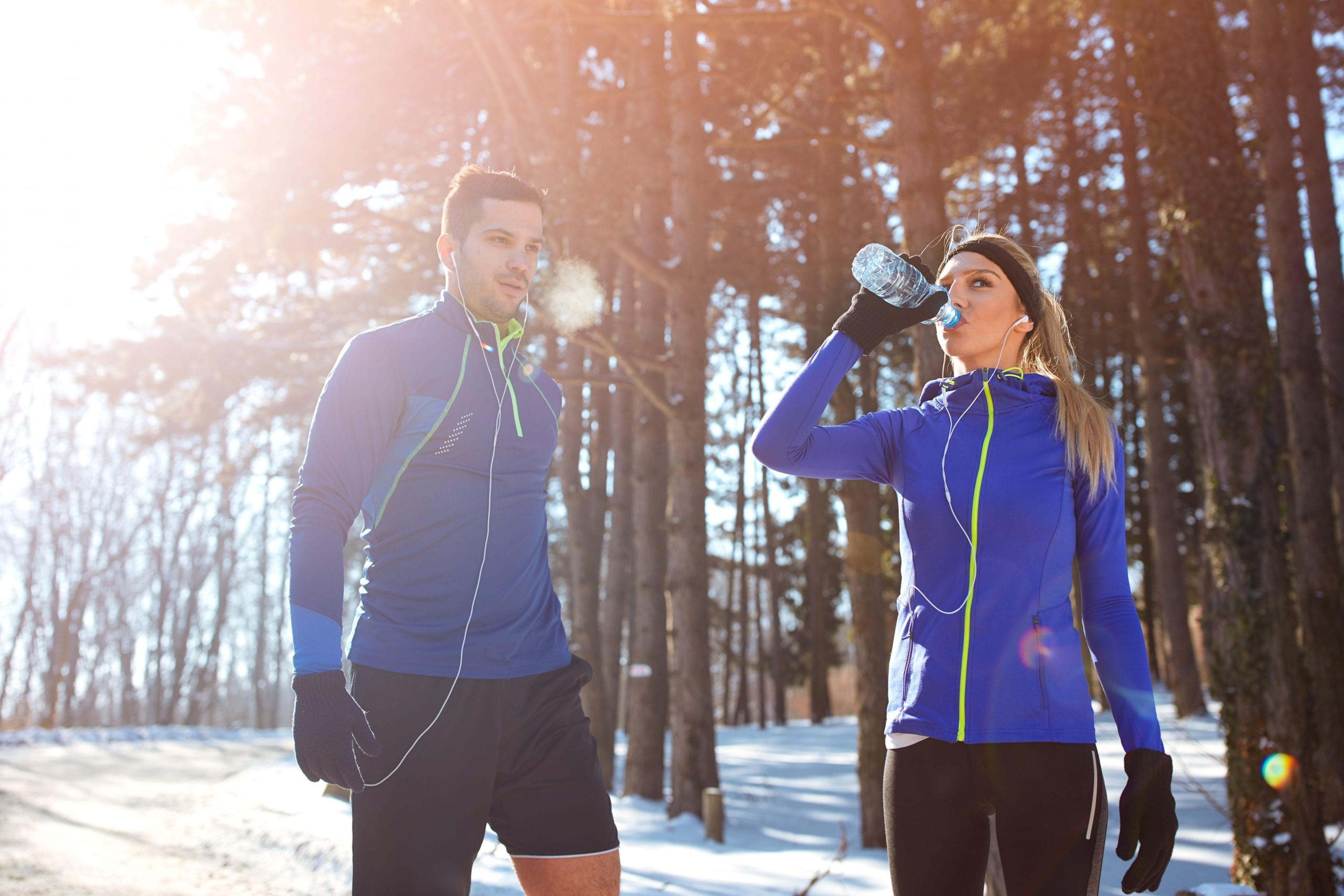 Couple resting from recreation in woods in winterCheerful female skier with skiing equipment