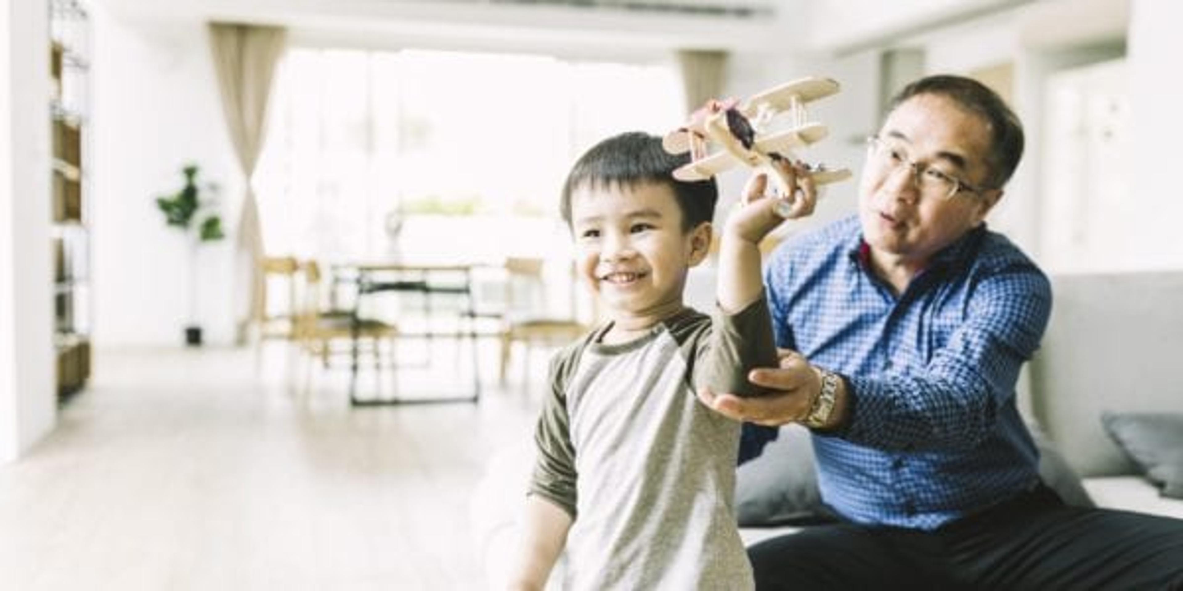 Grandfather with grandson flying an toy airplane