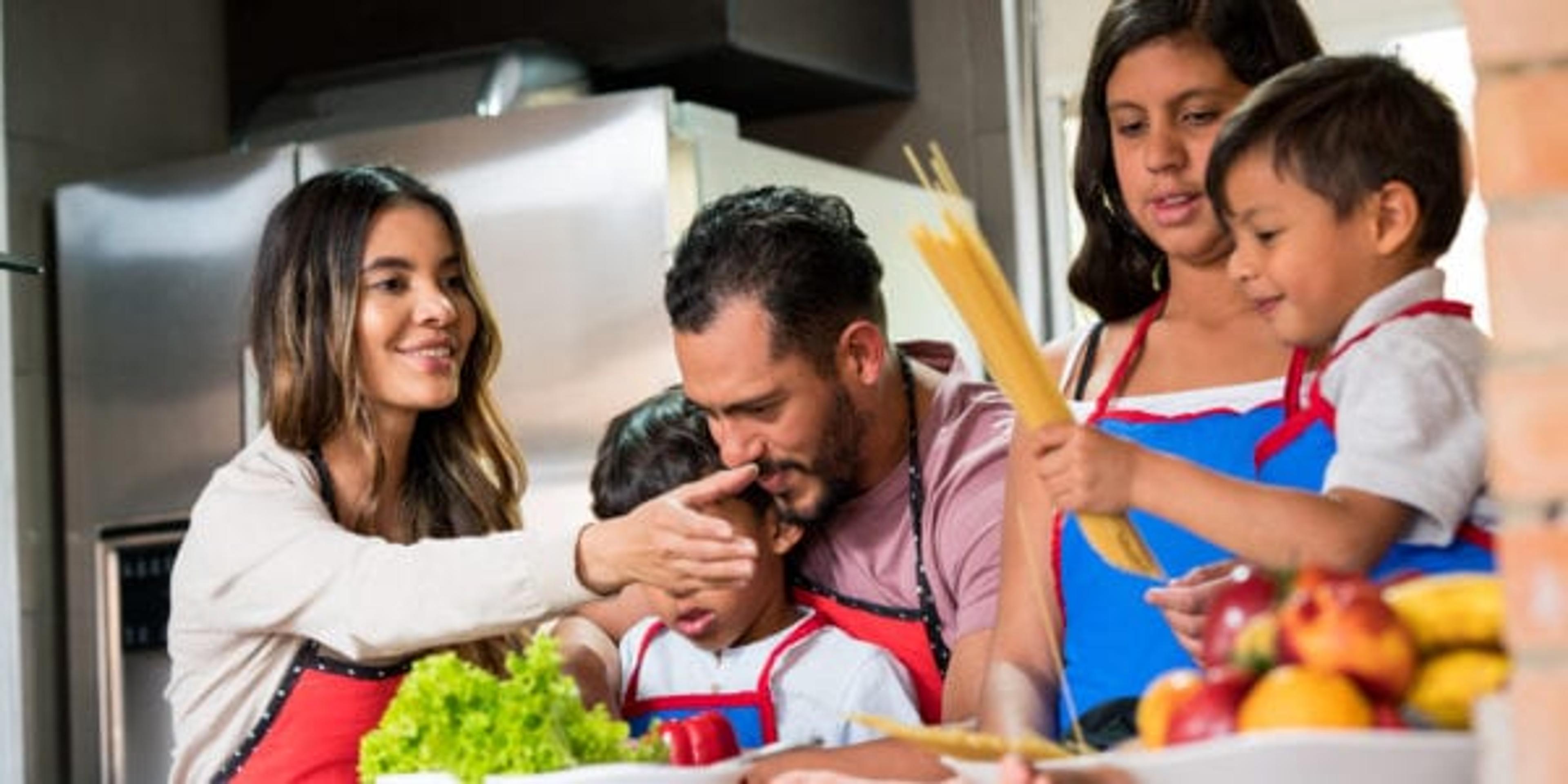 Latin family of five people, cooking spaghetti all together