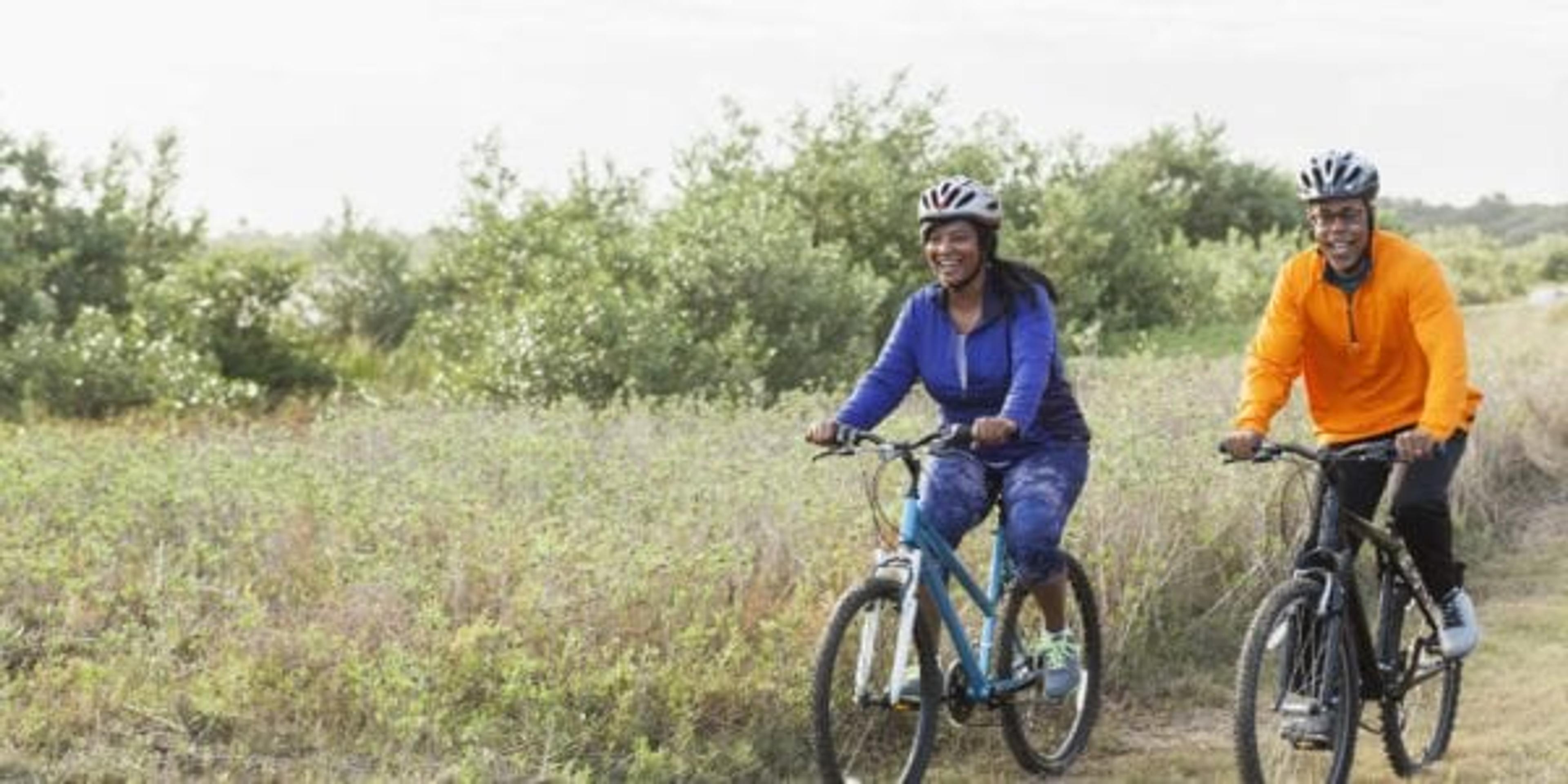 Mature African American couple riding bikes in park