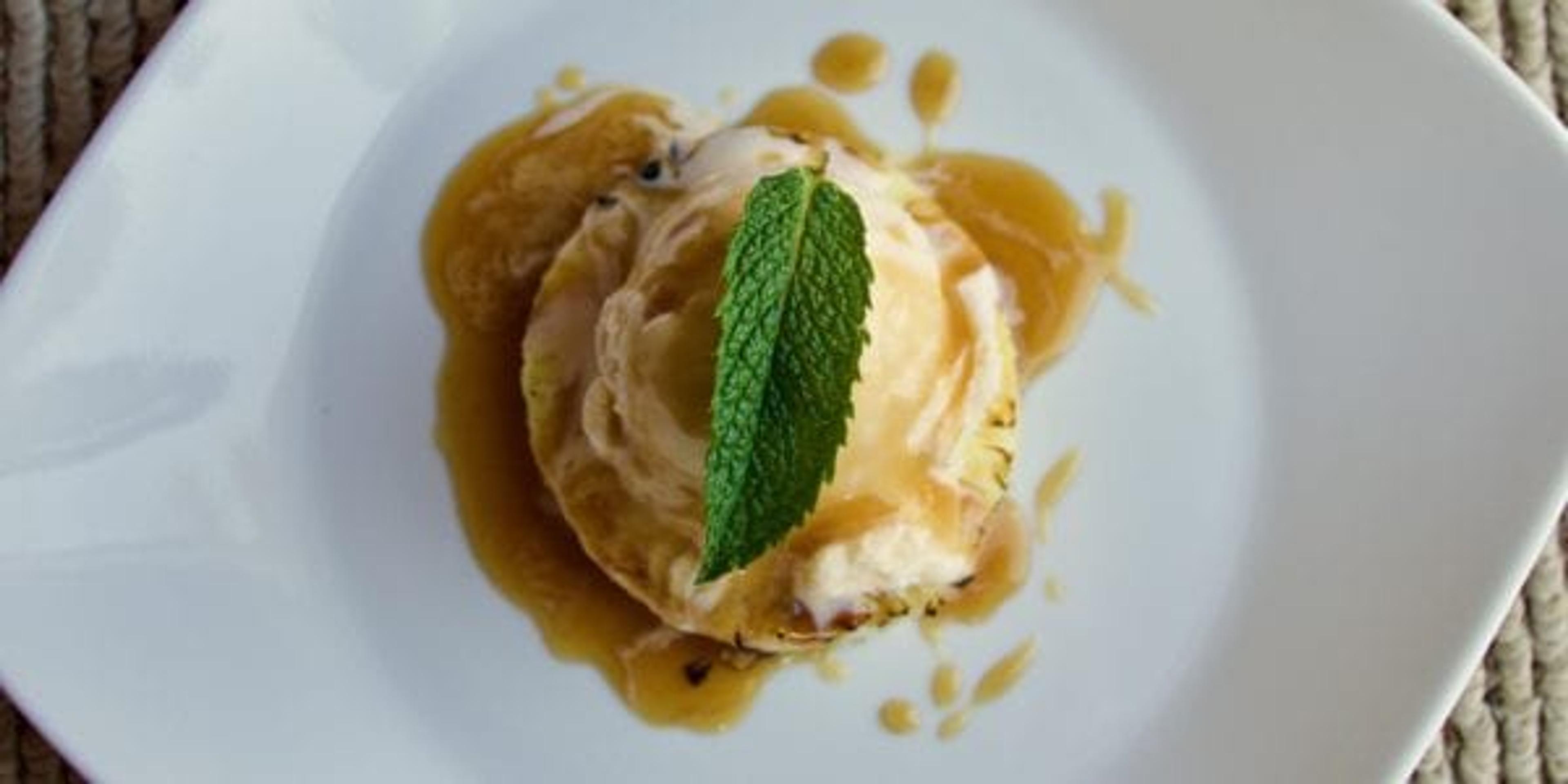 Grilled pineapple with vanilla frozen yogurt on a plate.