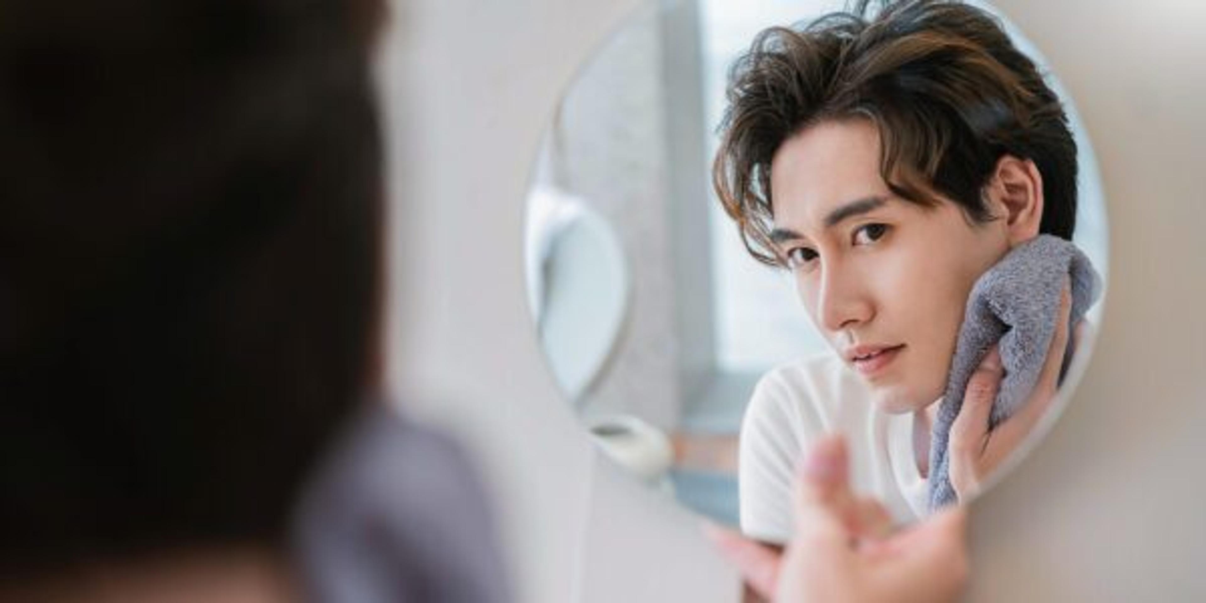Closeup portrait of handsome beautiful asian boy with mirror makeup routine with copy space. Beauty influencer guy with perfect glow skin dress up. Healthcare man lifestyle cosmetic blogger concept