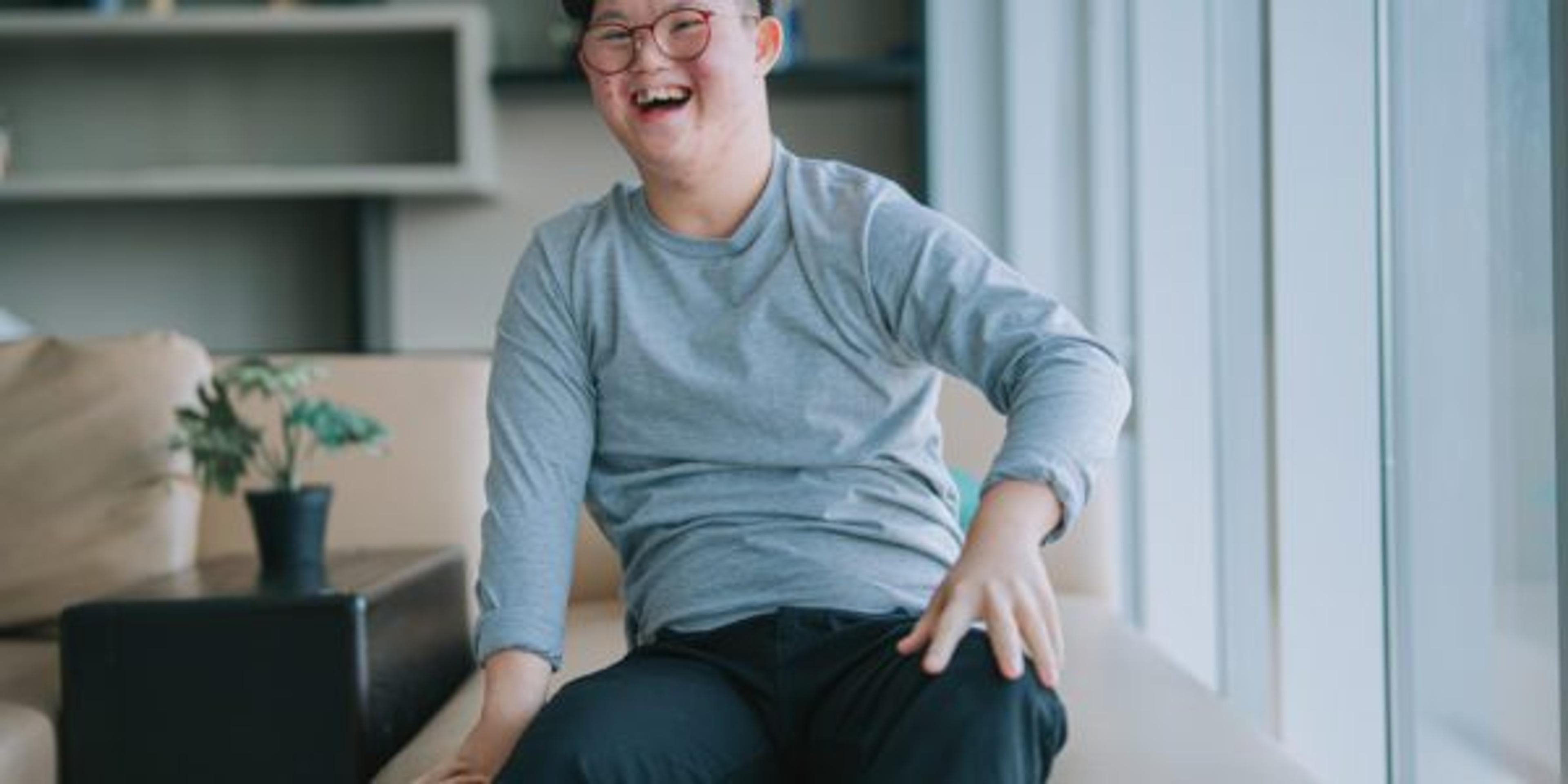 portrait Asian Chinese down syndrome young man looking at camera smiling in living room