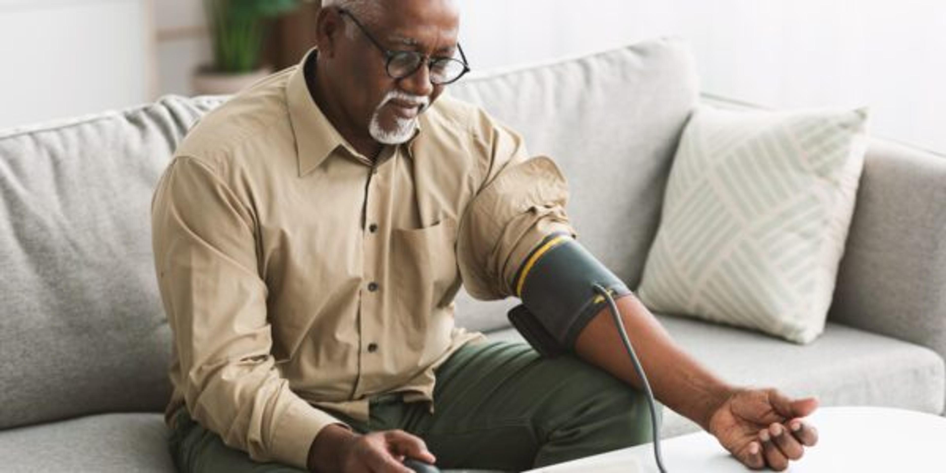 Senior African Male Measuring Arterial Blood Pressure Having Hypertension Indoor