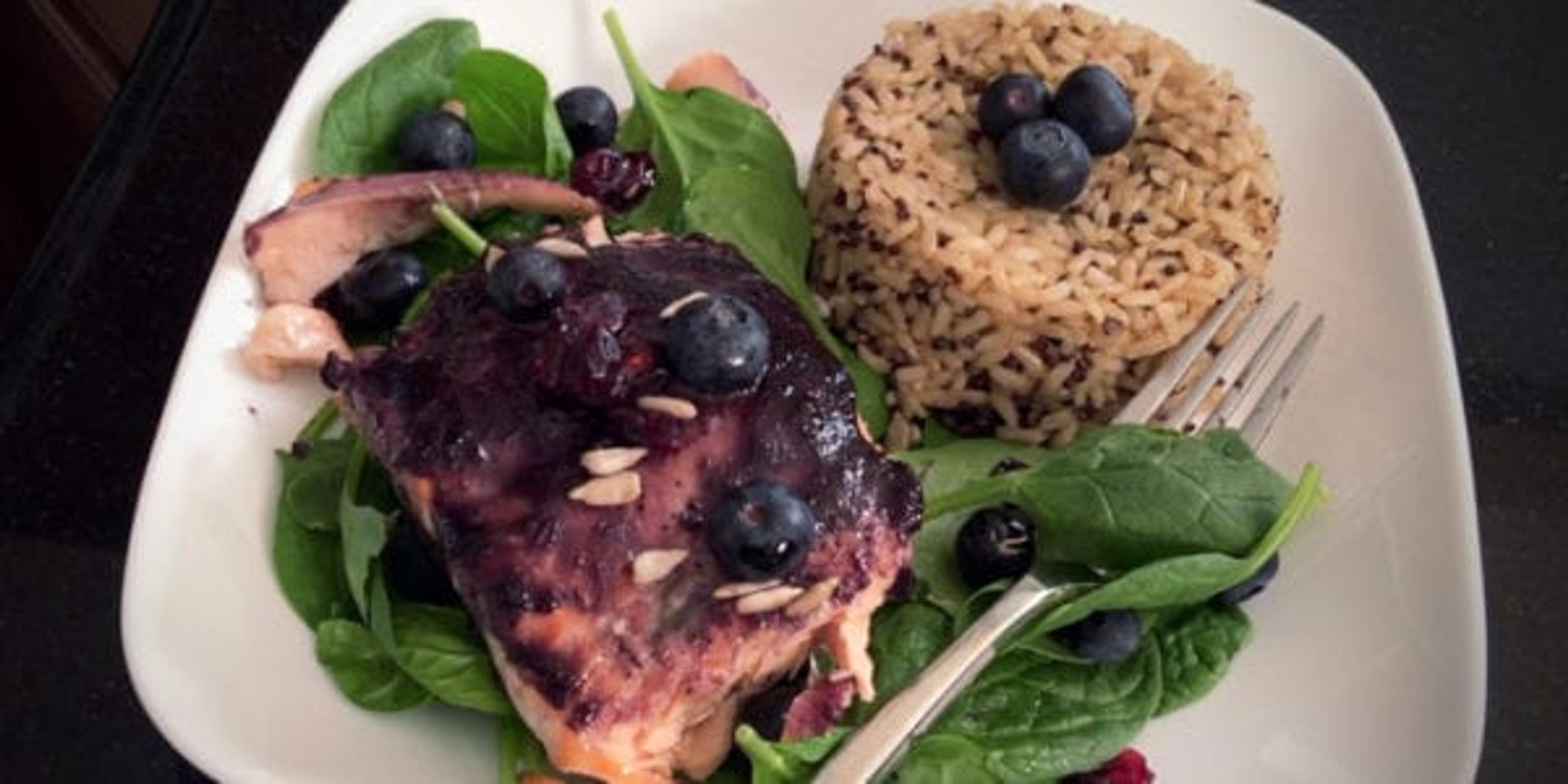 Salmon with blueberry glaze atop a bed of spinach and side of rice