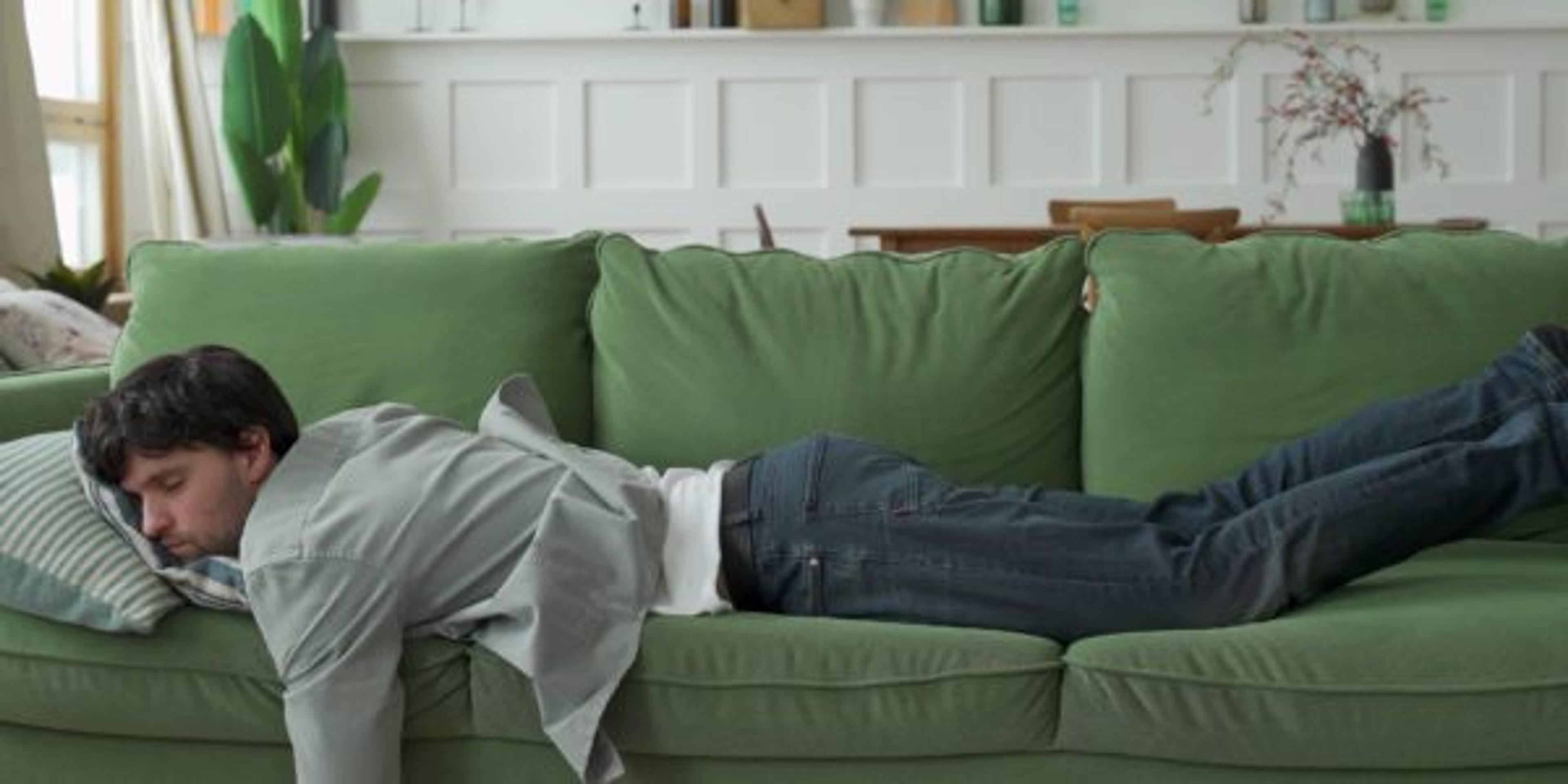 Exhausted young man came home after work flopped down on sofa