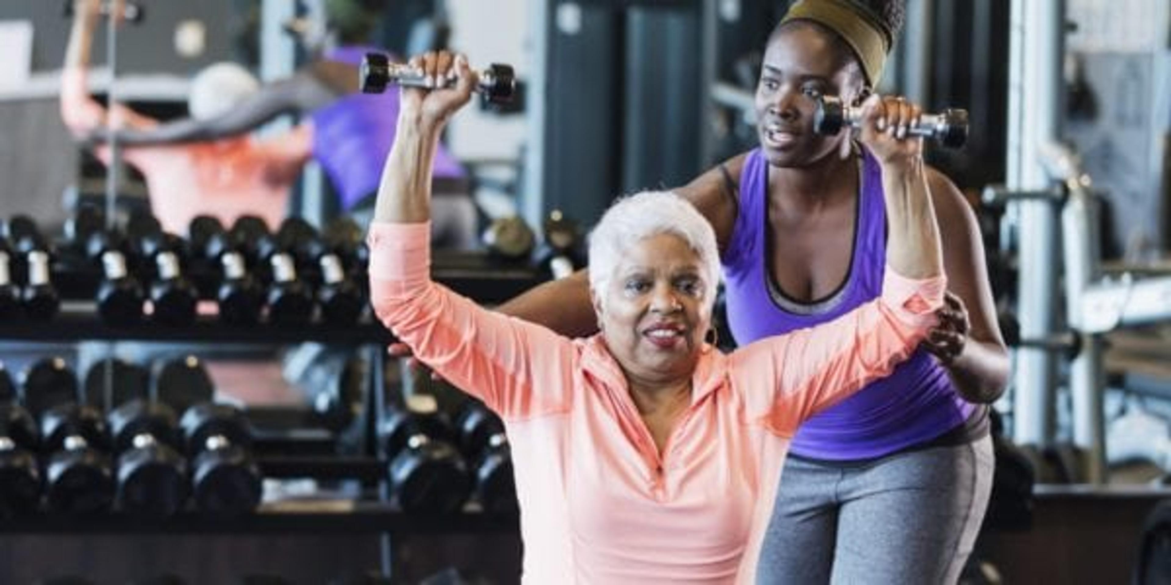 Young adult spotting senior adult during workout