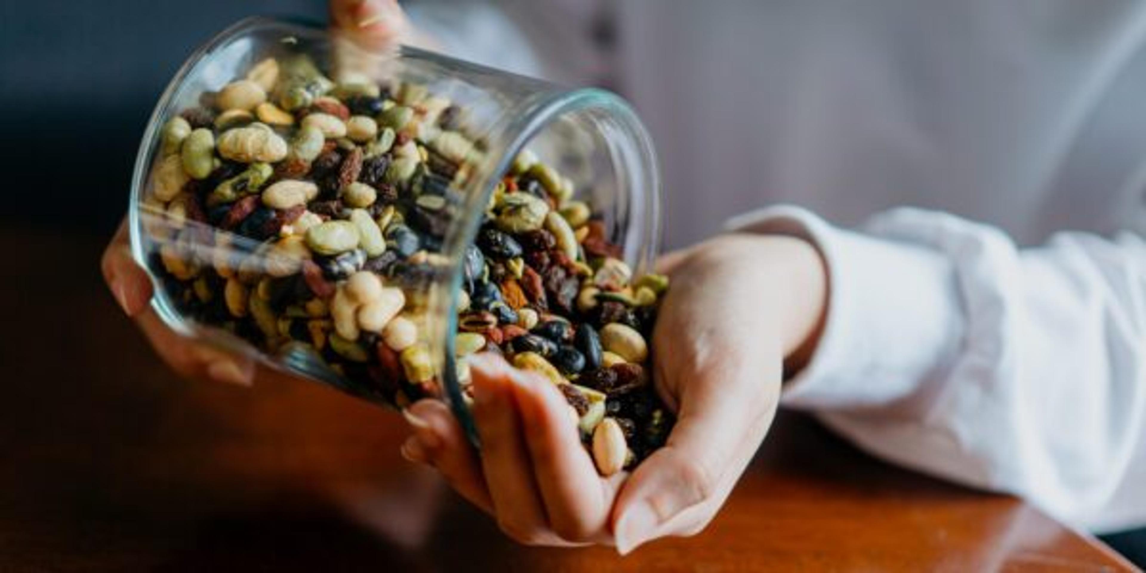 Asian woman hand holding glass hermetic pot with mix of nuts