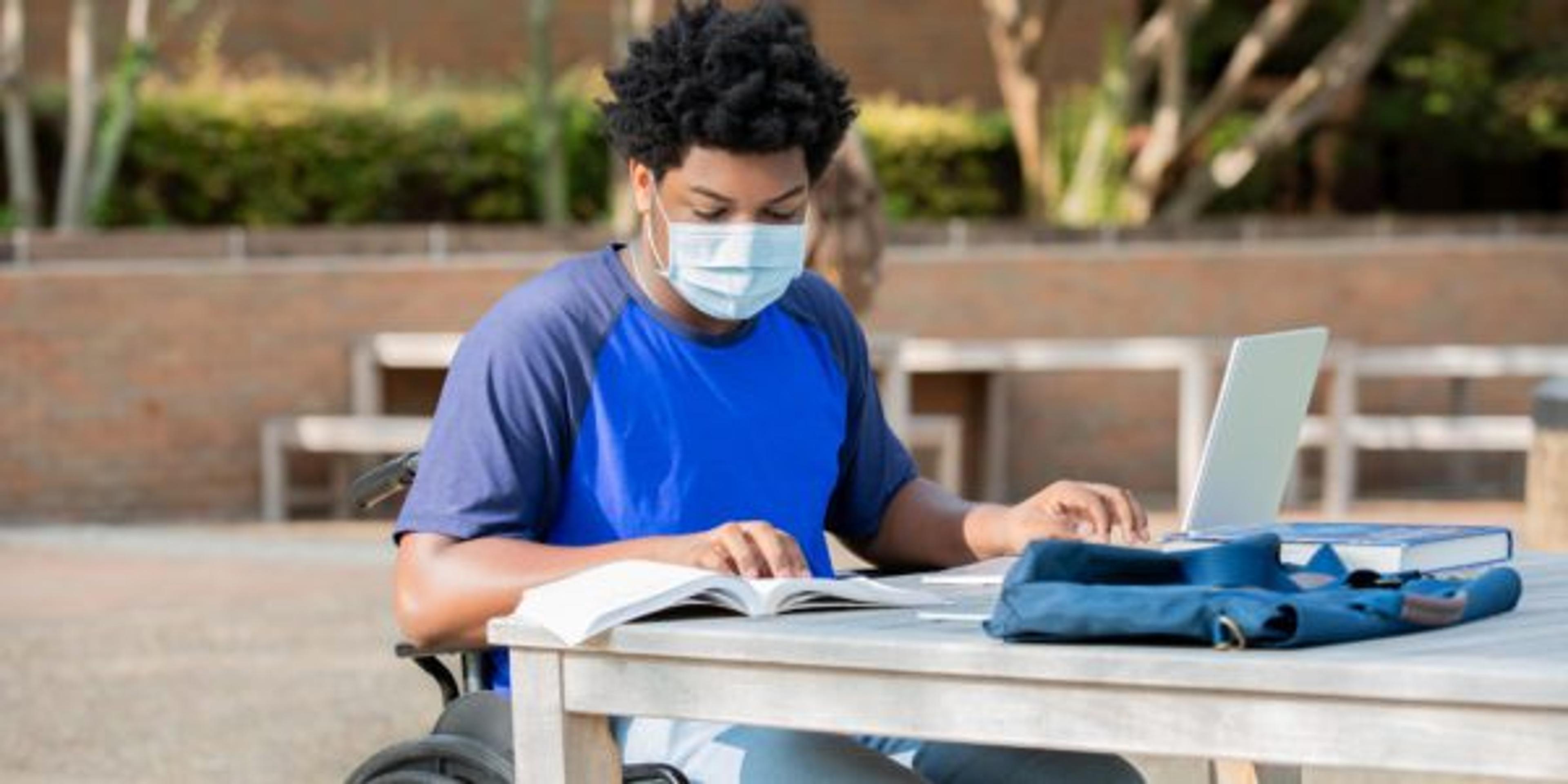 Disabled college student sitting at outdoor desk