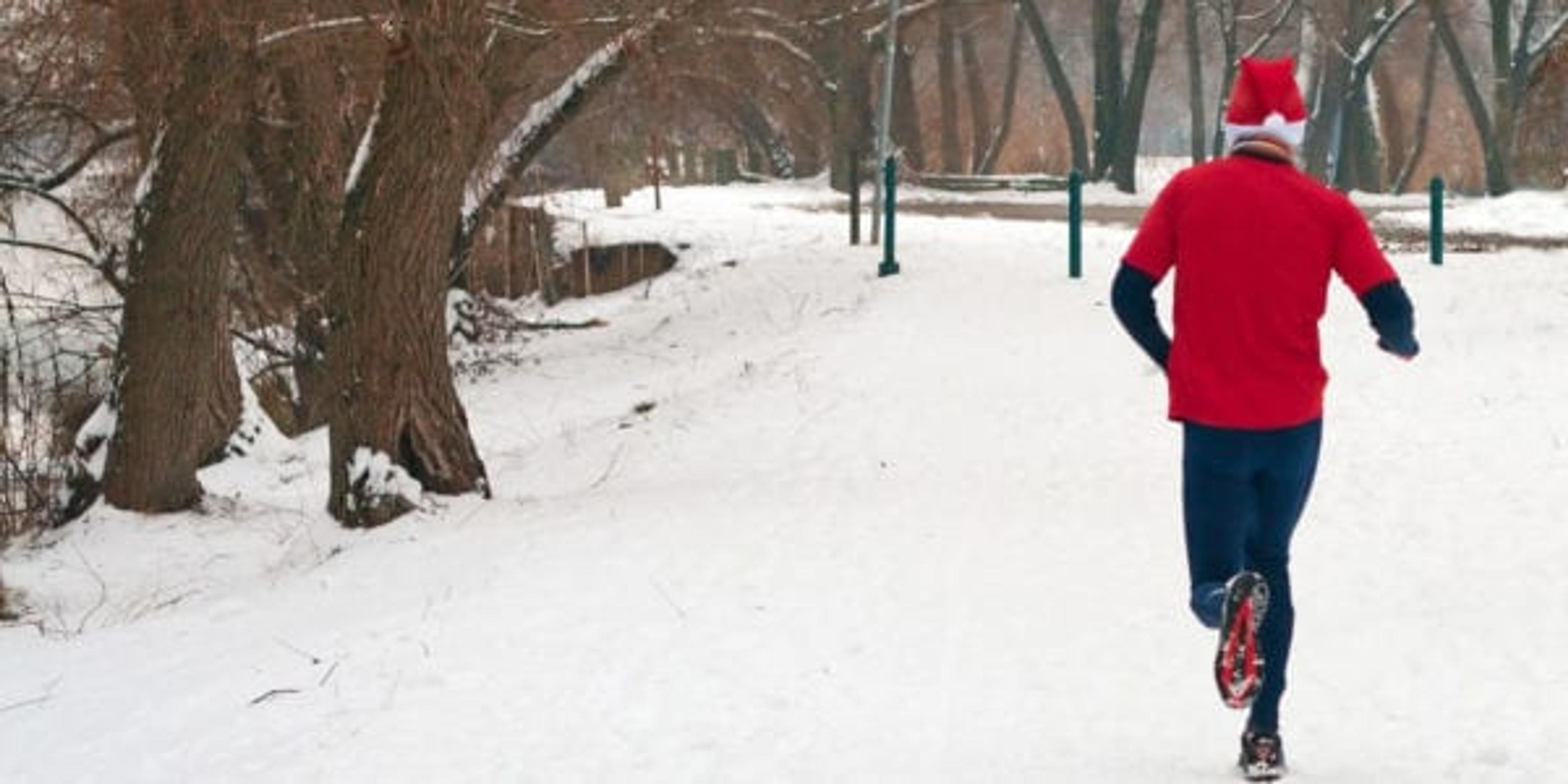 Man running in a Santa hat through snow.