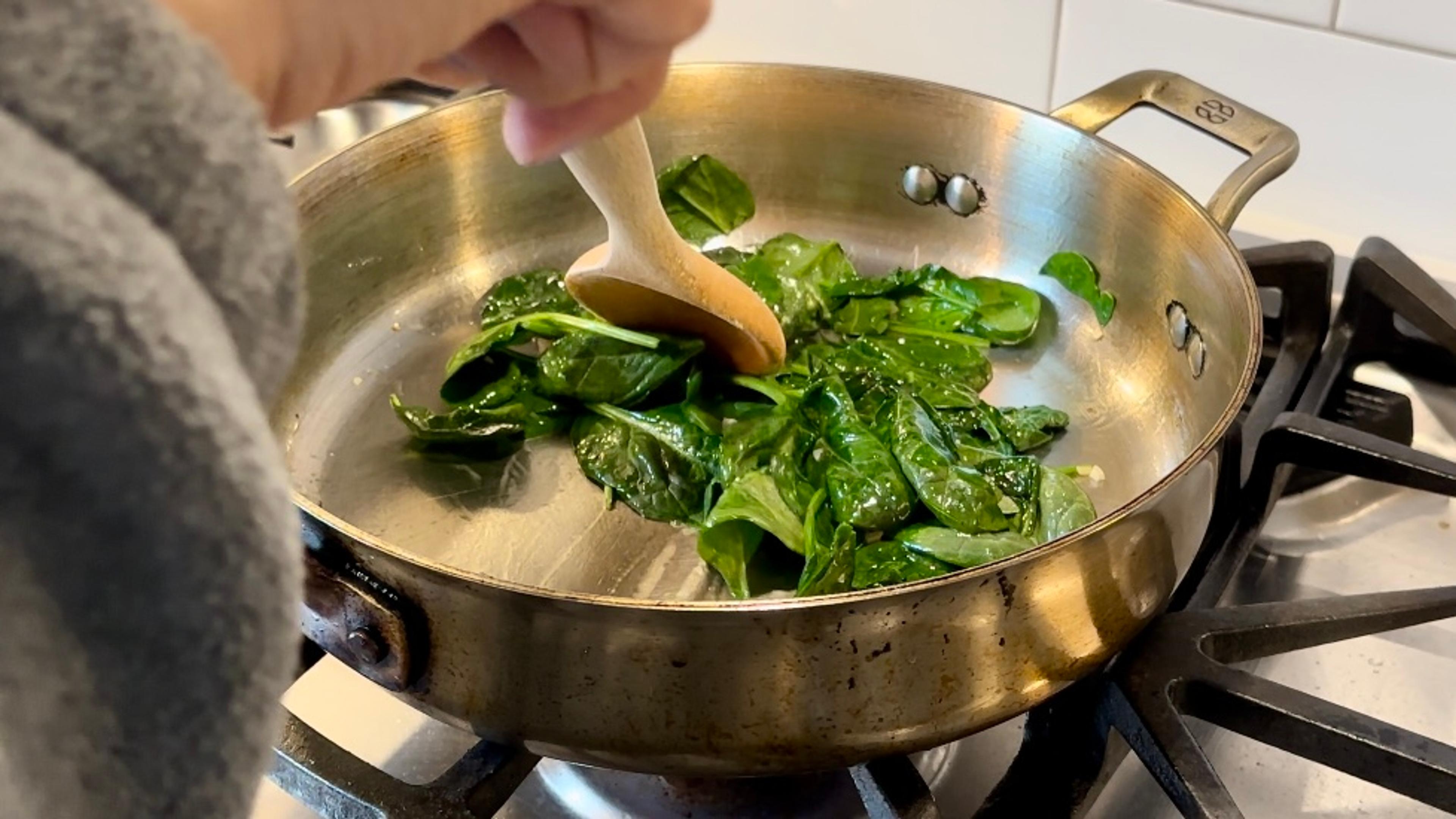Spinach and garlic in olive oil, in a skillet on the stovetop. 