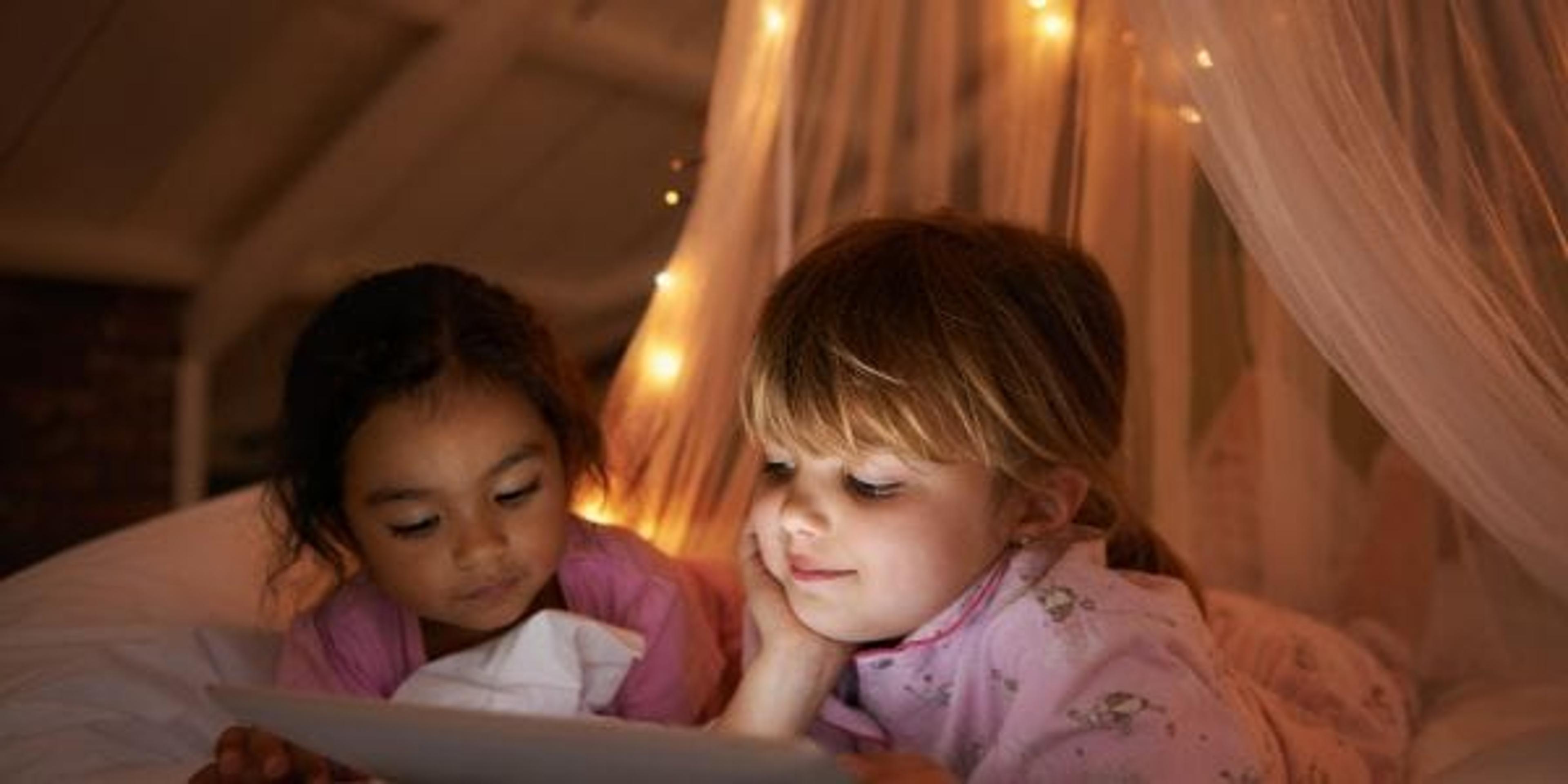 Two girls reading at night on a bed