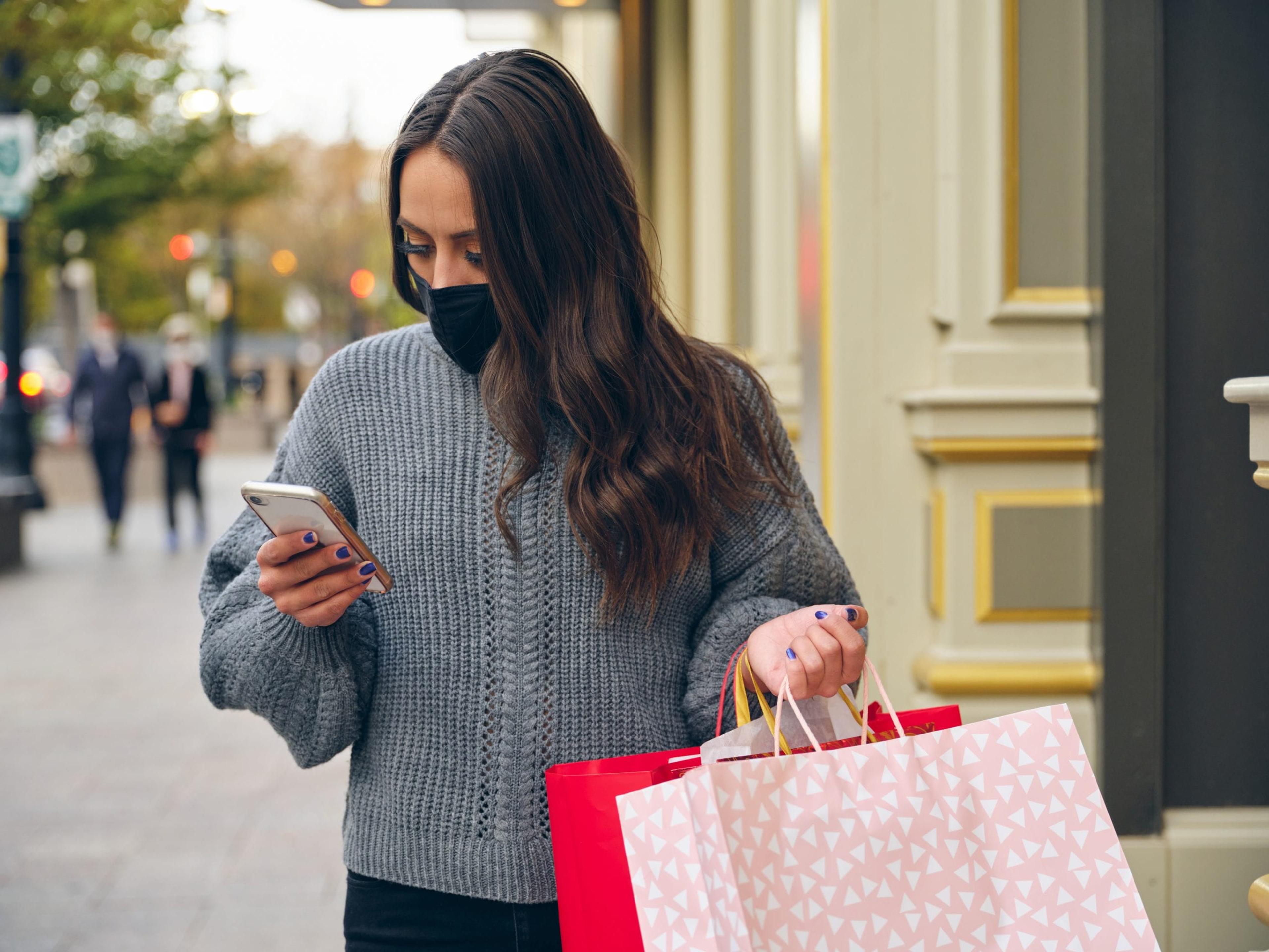 A young woman, shopping in a downtown area wearing facemasks for protection.