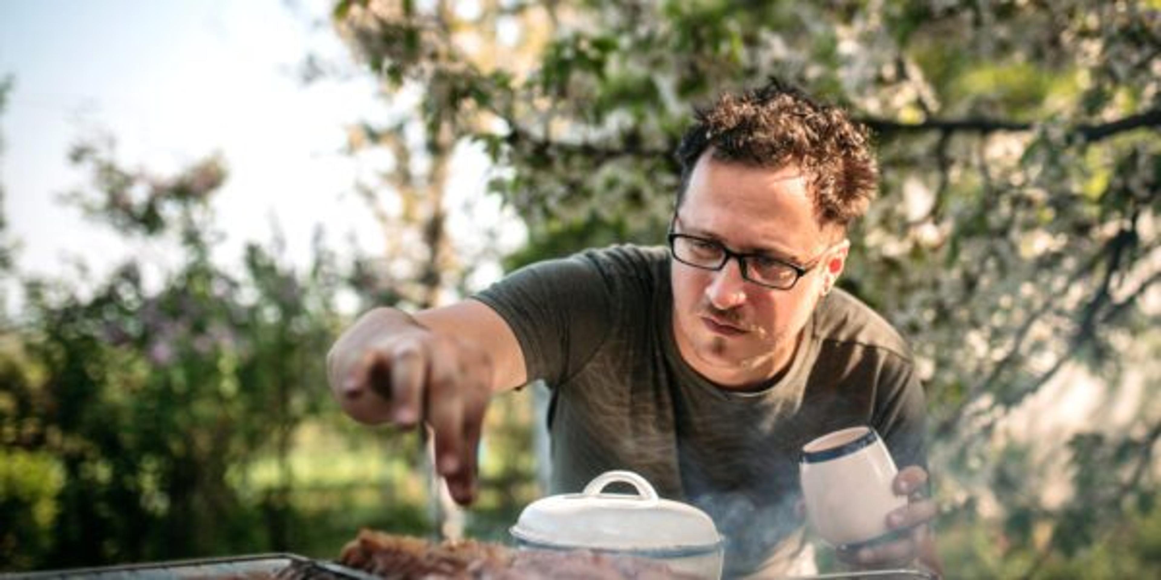 Man seasoning meat on the grill