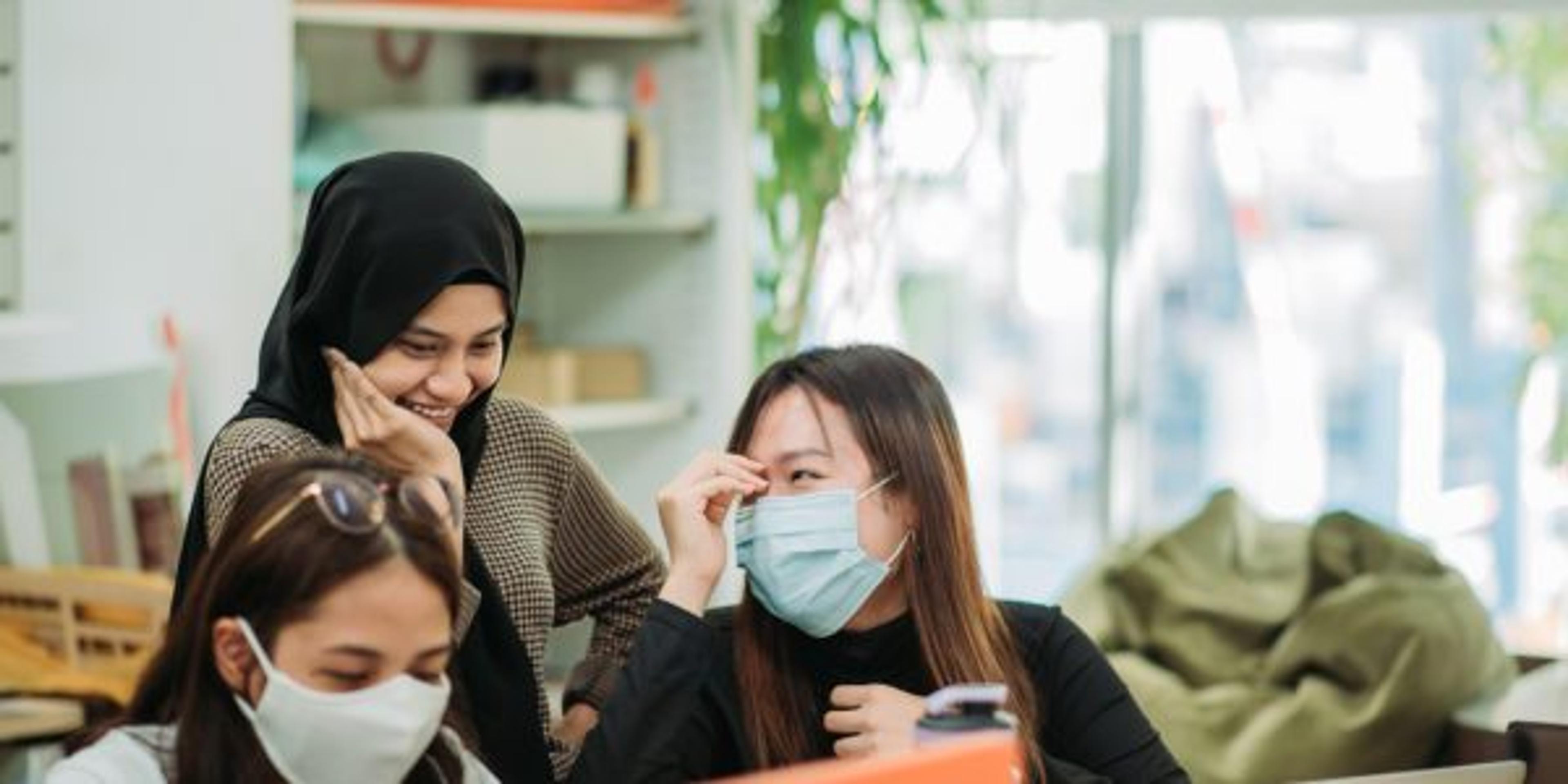 Asian malay smiling hijap female having fun with her classmate in college classroom