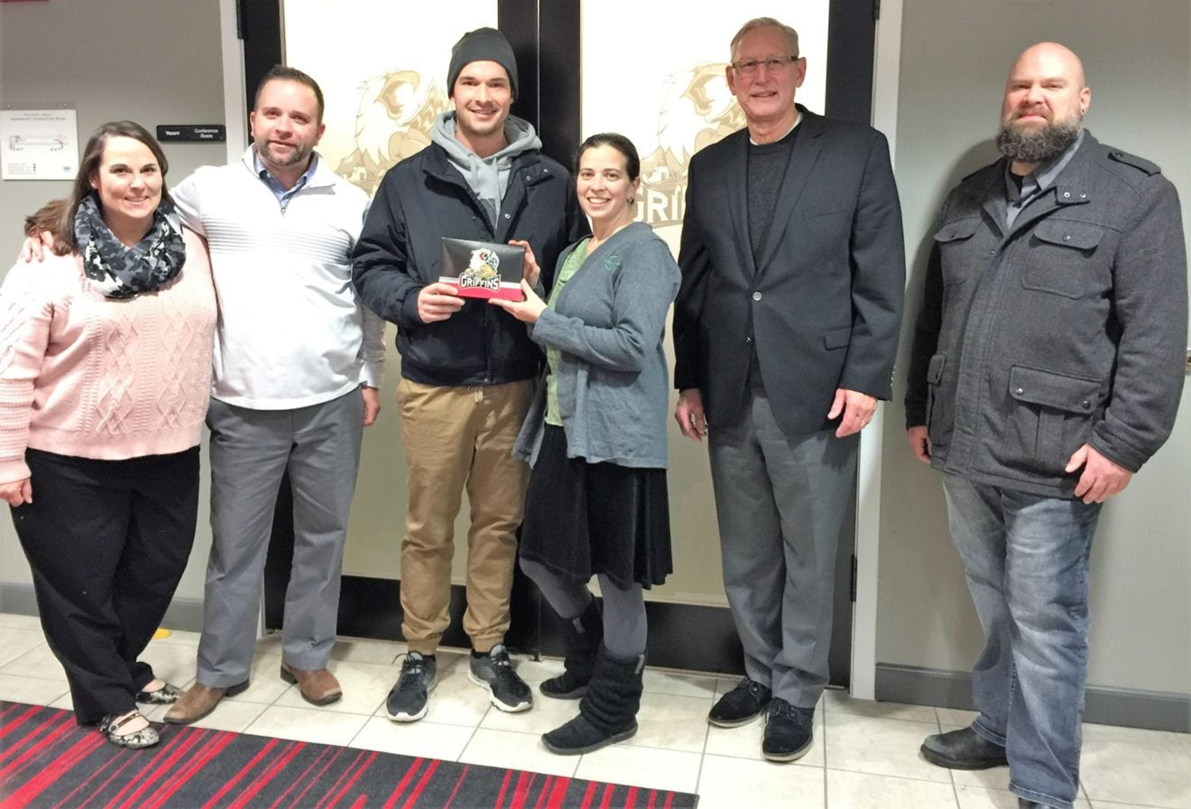 Matt Puempel presents season tickets to Arbor Circle representatives, with support from Blue Cross Blue Shield of Michigan.