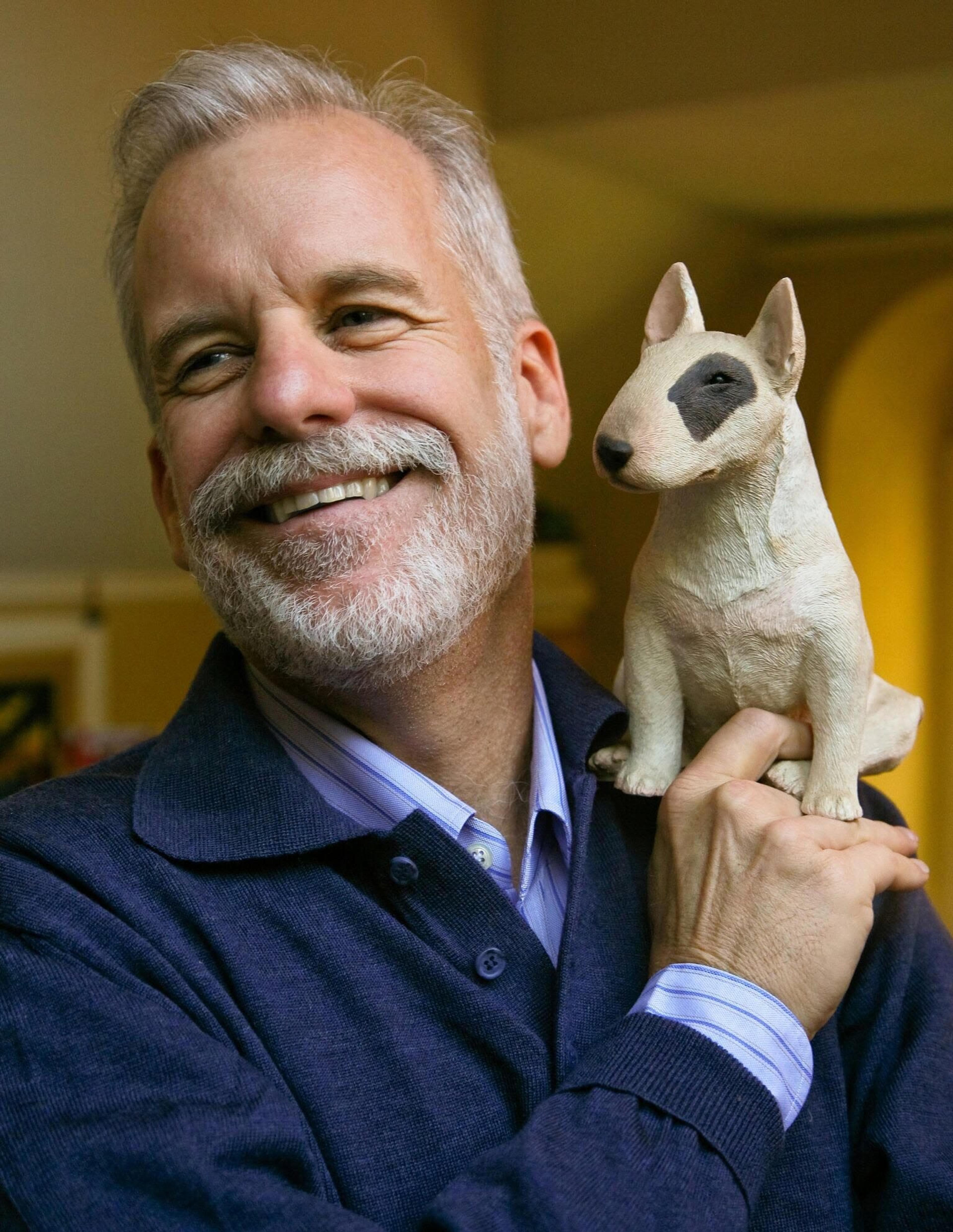 Chris VanAllsburg with a tiny dog perched on his shoulder.