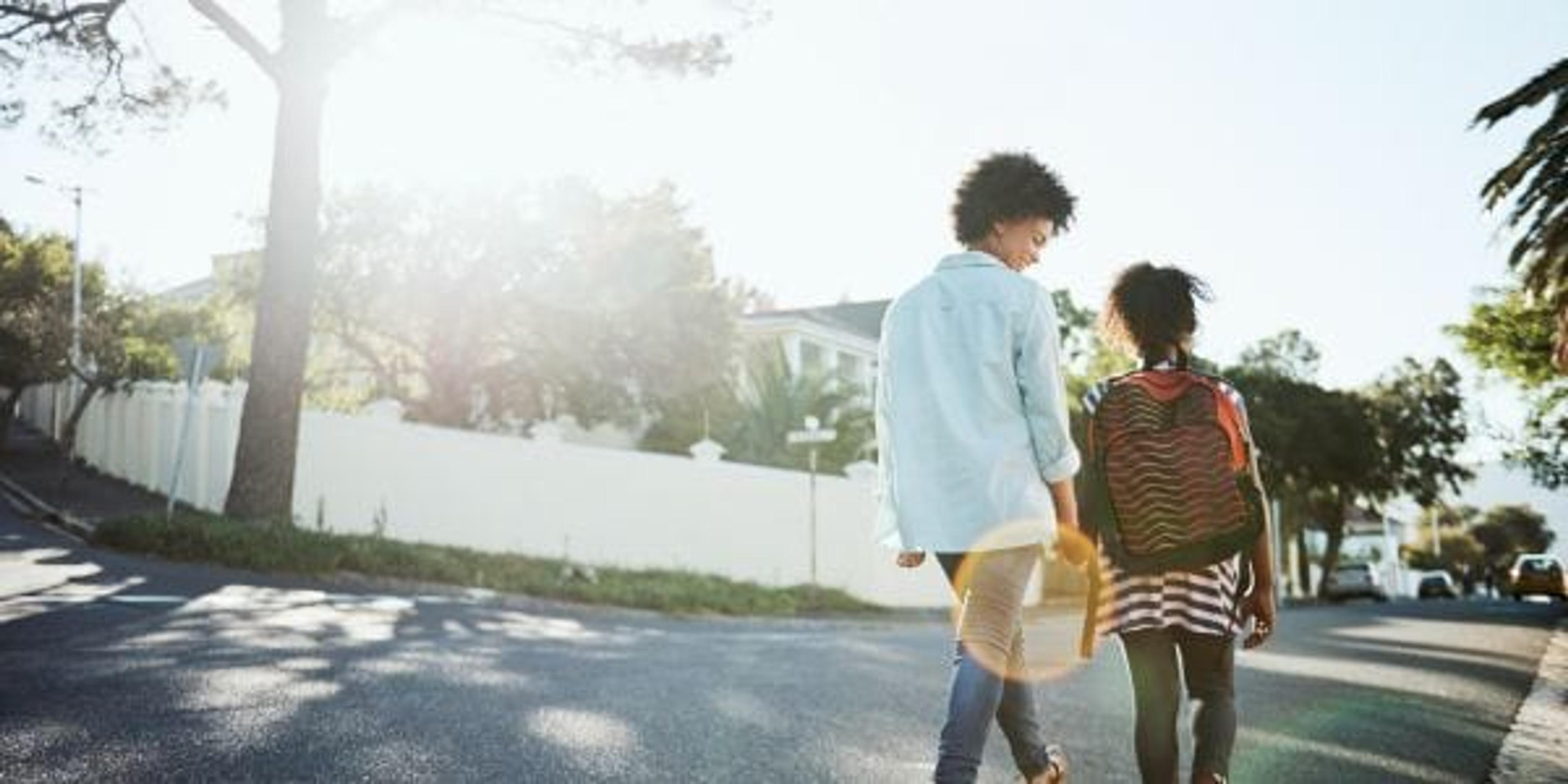 Rearview shot of a cheerful young mother and her daughter walking down the street together outside during the day