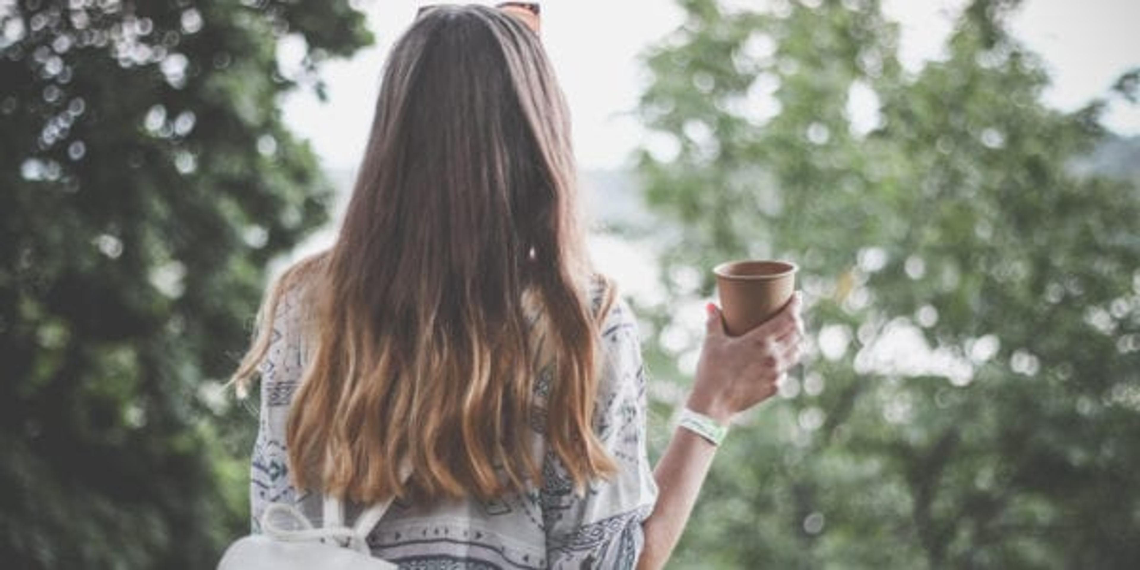 Girl with brown hair facing away from camera holding a small pot.